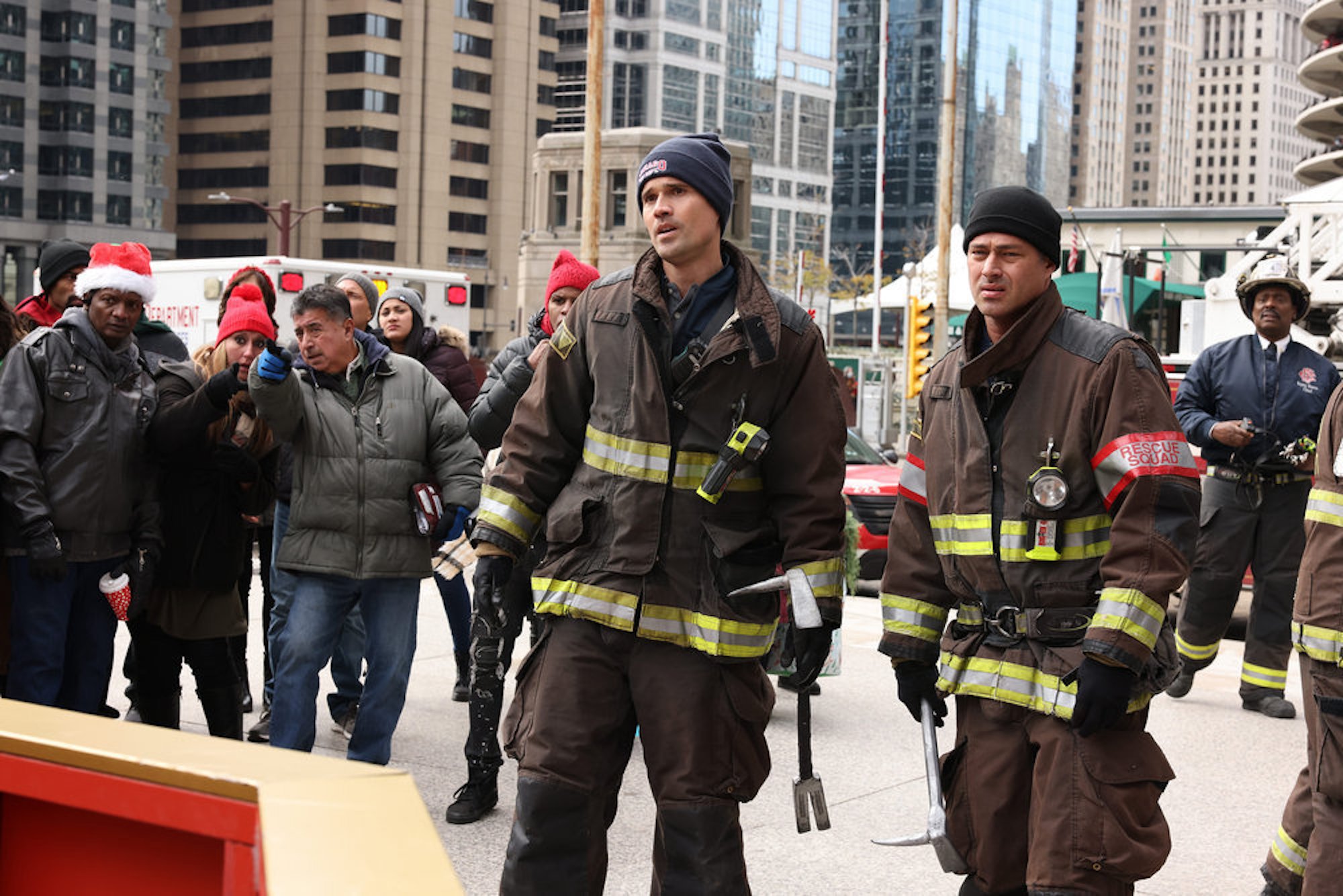 Brett Dalton as Jason Pelham and Taylor Kinney as Kelly Severide in firefighting uniforms amongst a crowd in the 'Chicago Fire' Season 10 fall finale