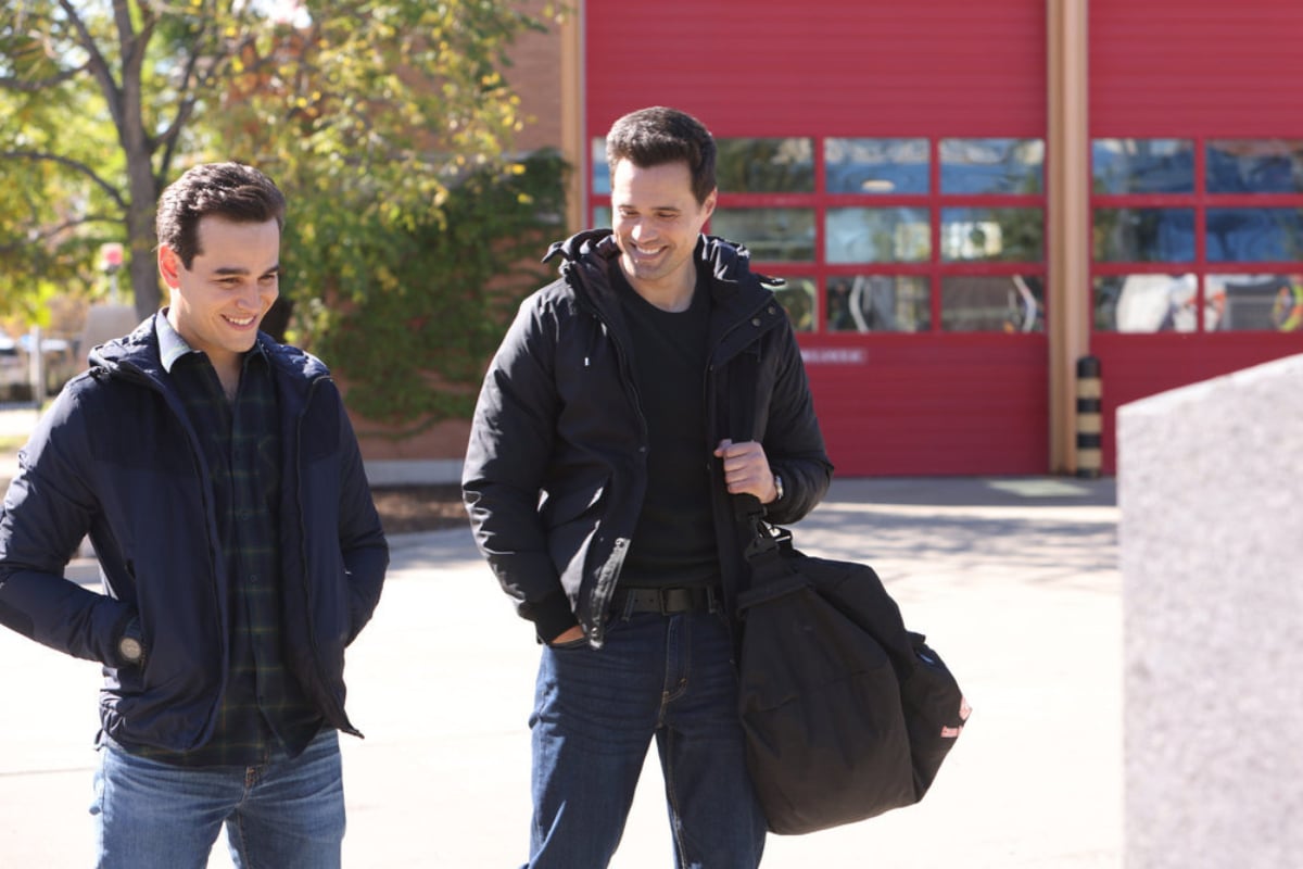 Alberto Rosende as Blake Gallo, Brett Dalton at Jason Pelham in Chicago Fire Season 10. Gallo and Pelham are smiling and standing next to each other.