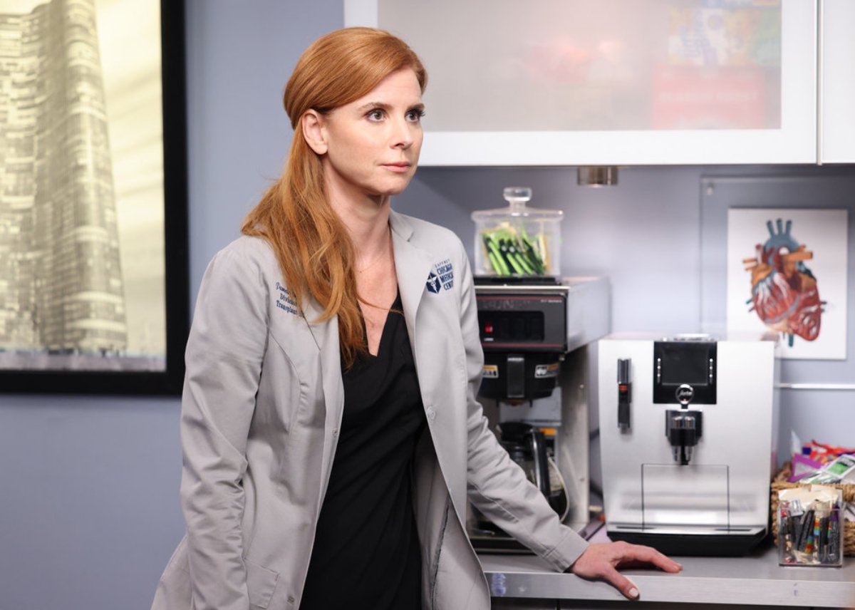 Sarah Rafferty as Dr. Pamela Blake in Chicago Med Season 7. Blake is wearing black scrubs and a lab coat.