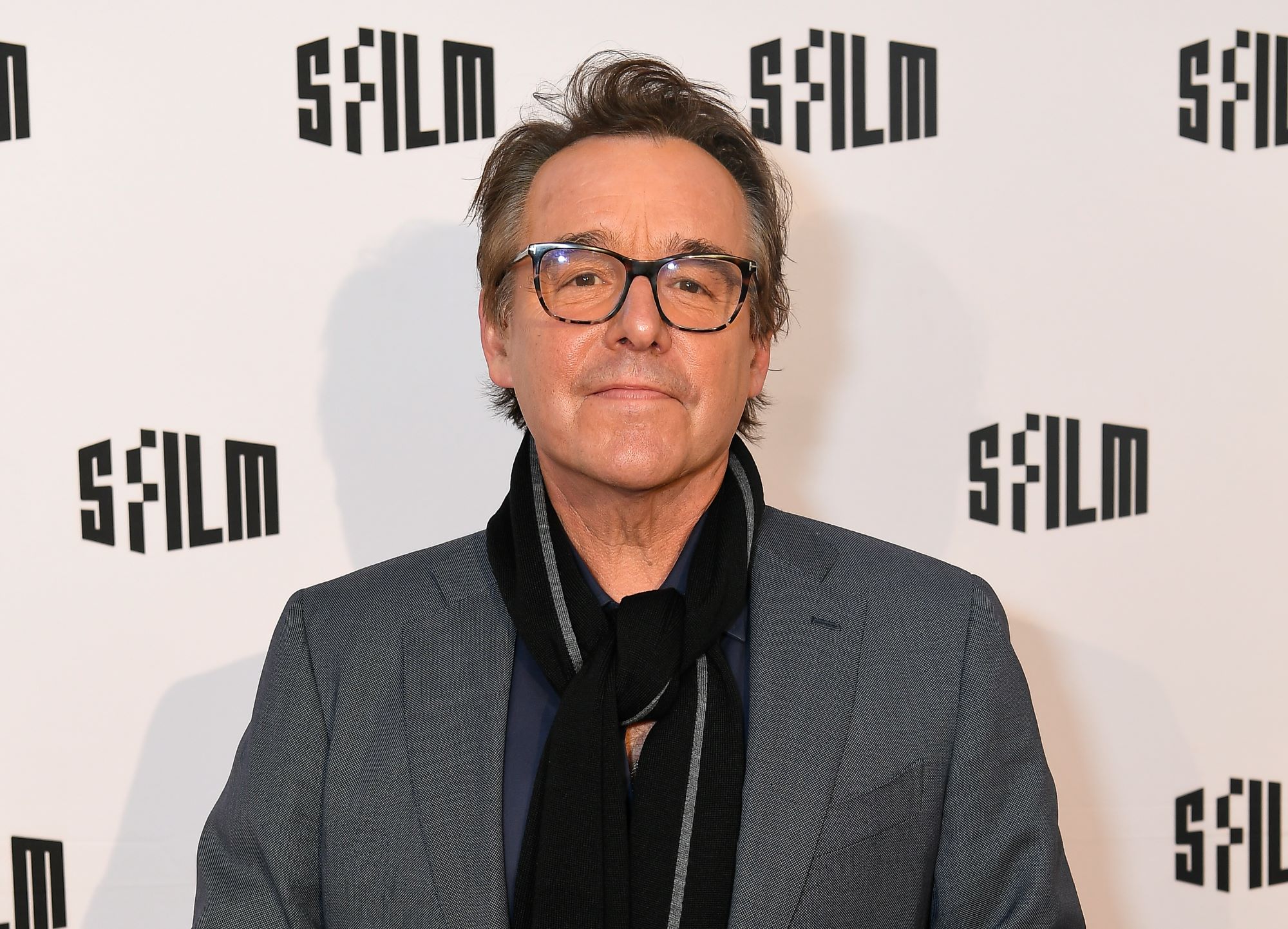 'Home Alone' director Chris Columbus, who was the original director of 'National Lampoon's Christmas Vacation,' wears a gray suit jacket over a blue shirt and a black scarf.
