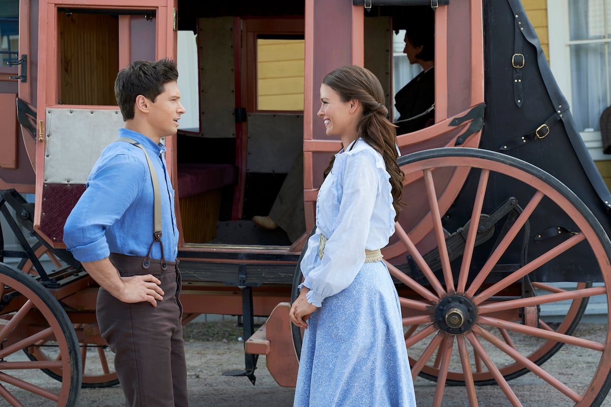 Chuck and Grace smiling at each other in front of a stagecoach in 'When Hope Calls' Season 1