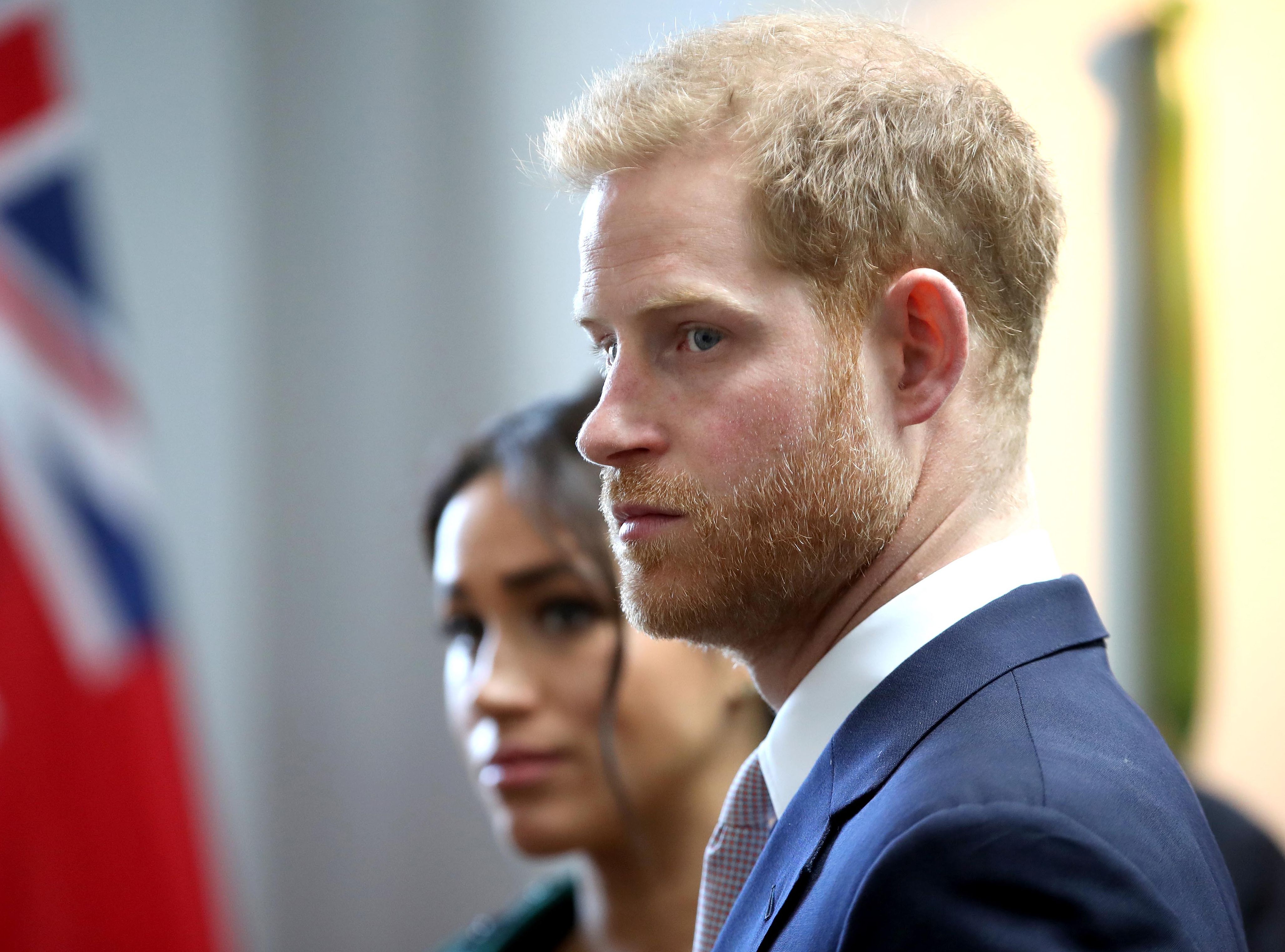Closeup of Prince Harry's profile with Meghan Markle in the background