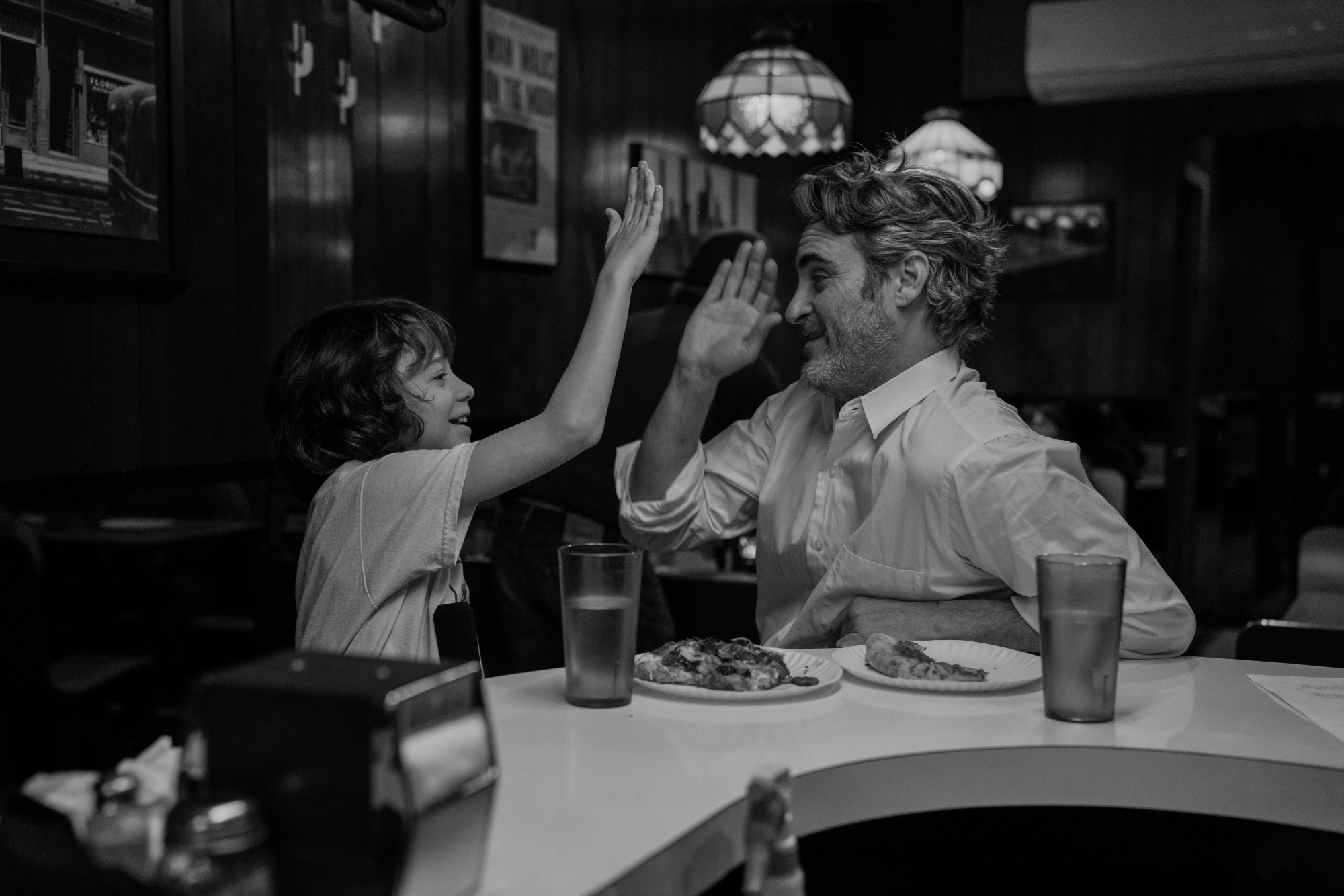 'C'mon C'mon' Woody Norman as Jesse and Joaquin Phoenix as Johnny high-fiving at a restaurant counter