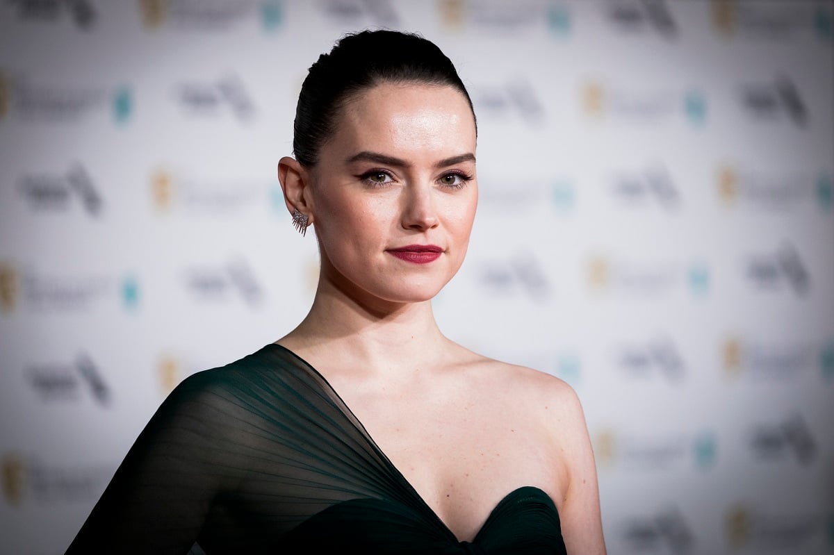 Daisy Ridley smiling in a black dress.