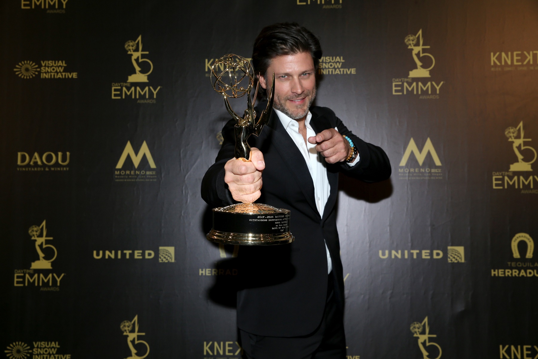 Days of Our Lives star Greg Vaughan holding an Emmy and wearing a black tuxedo