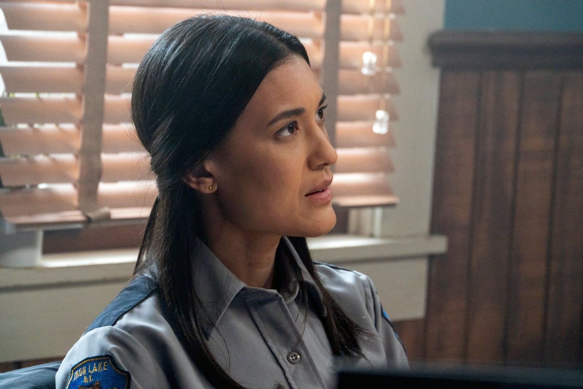 Julia Jones as Angela in Dexter: New Blood. Angela is wearing a button-up police uniform and has her hair half up.