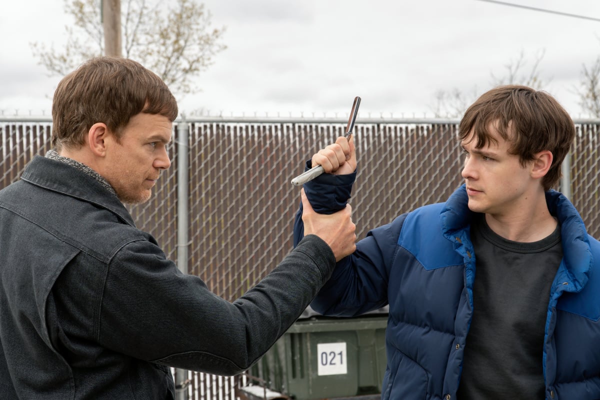 Michael C. Hall as Dexter and Jack Alcott as Harrison in Dexter: New Blood. Dexter grabs Harrison's arm as he hold's Trinity's razor blade.