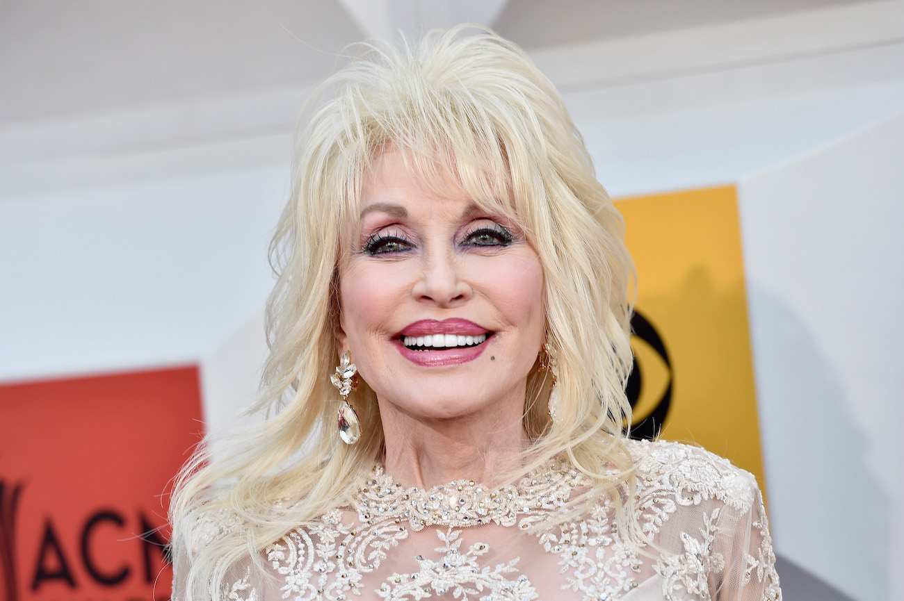 Dolly Parton smiles in a white dress as she poses for cameras at the 2016 Academy of Country Music Awards