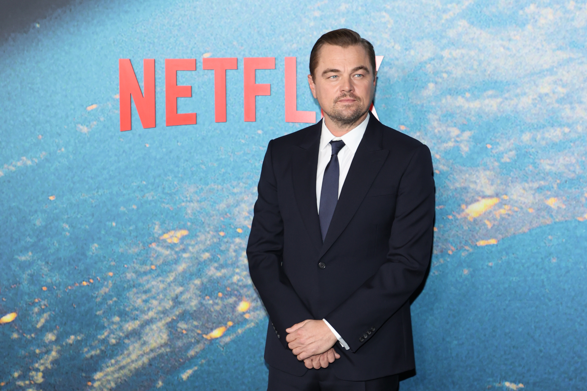 'Don't Look Up' star Leonardo DiCaprio in article about Meryl Streep nude scene standing in front of Netflix logo in a suit