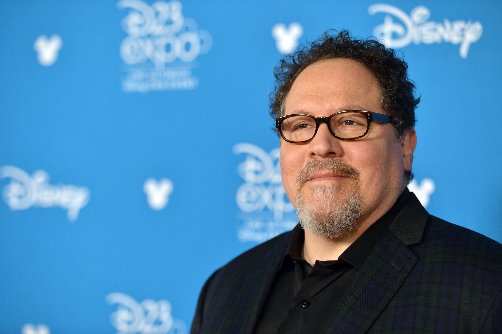 'Elf' Jon Favreau talking North Pole scenes standing in front of blue step and repeat