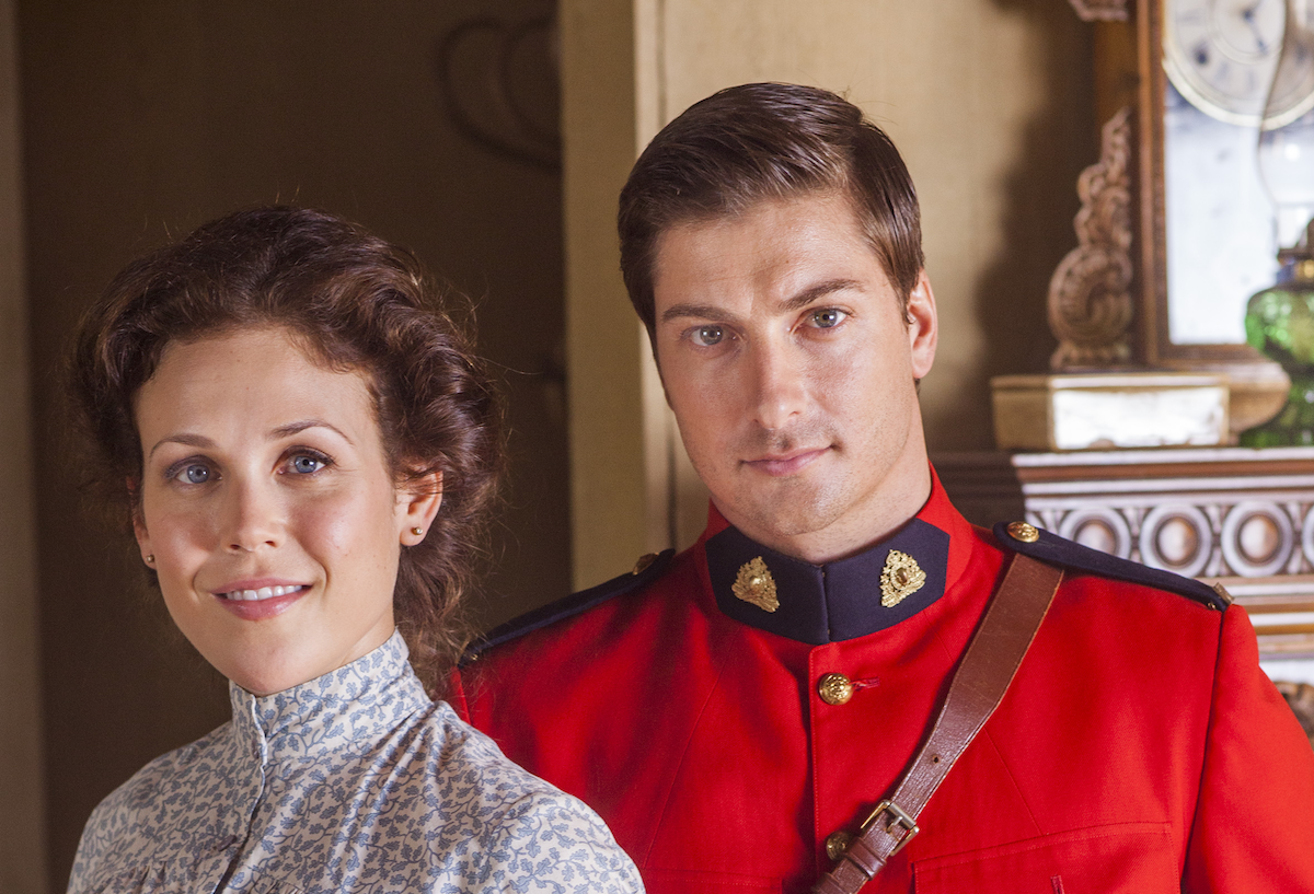 Elizabeth, wearing a high-necked dress, and Jack, wearing a red Mountie jacket, in ''When Calls the Heart' Season 1
