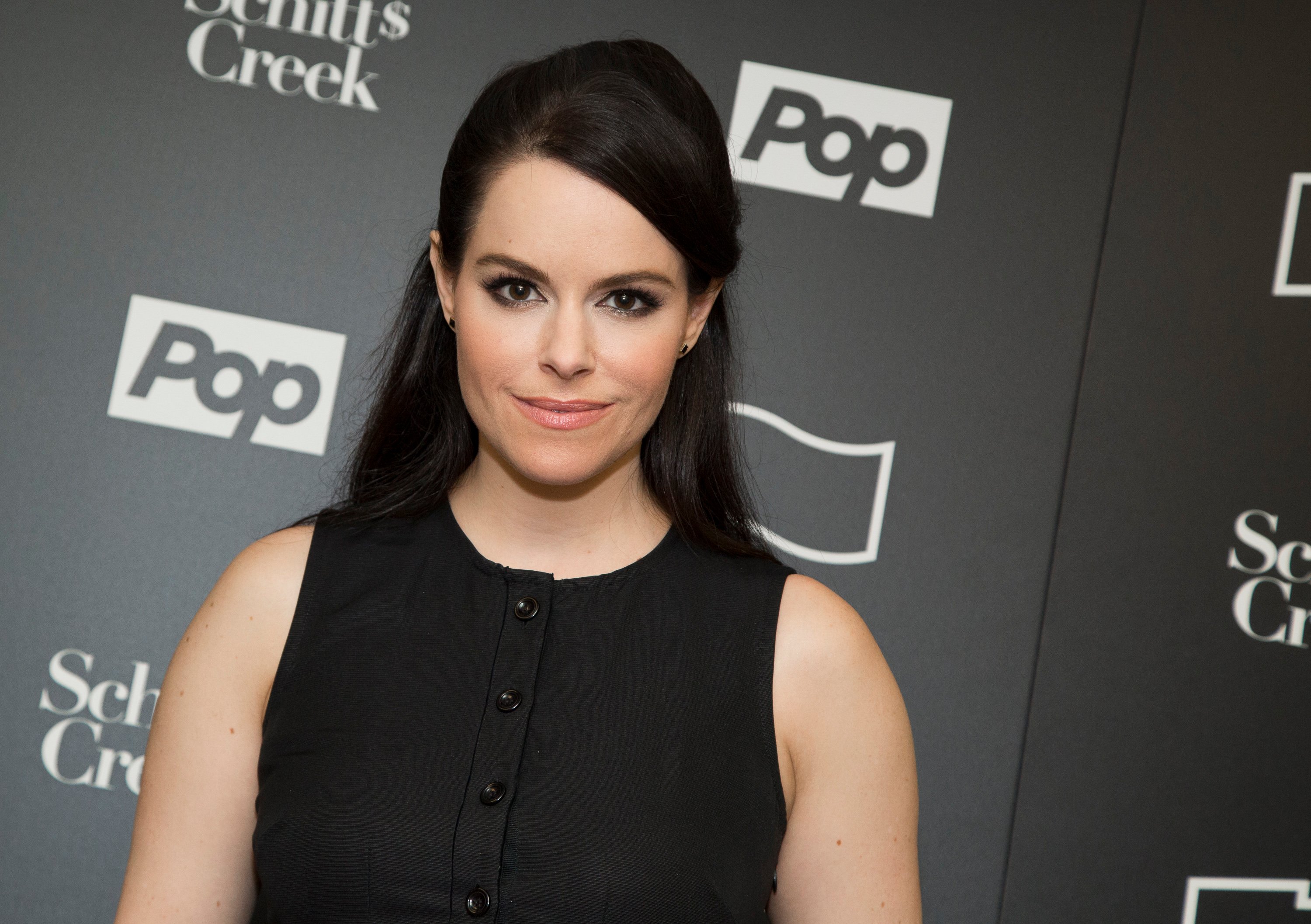 'Schitt's Creek' star Emily Hampshire poses at an event wearing a black dress