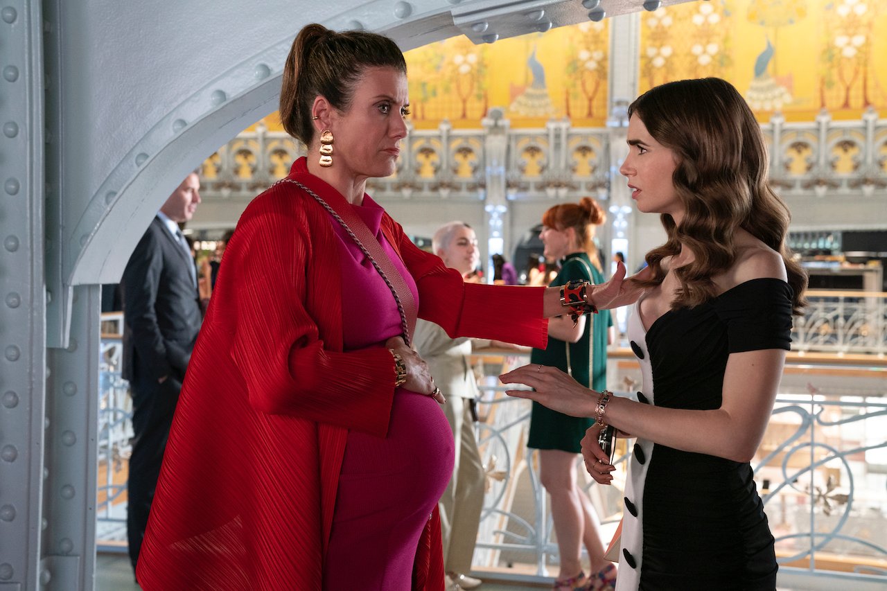 L to R) Kate Walsh as Madeline stands holding her pregnant belly with Lily Collins as Emily in 'Emily in Paris'