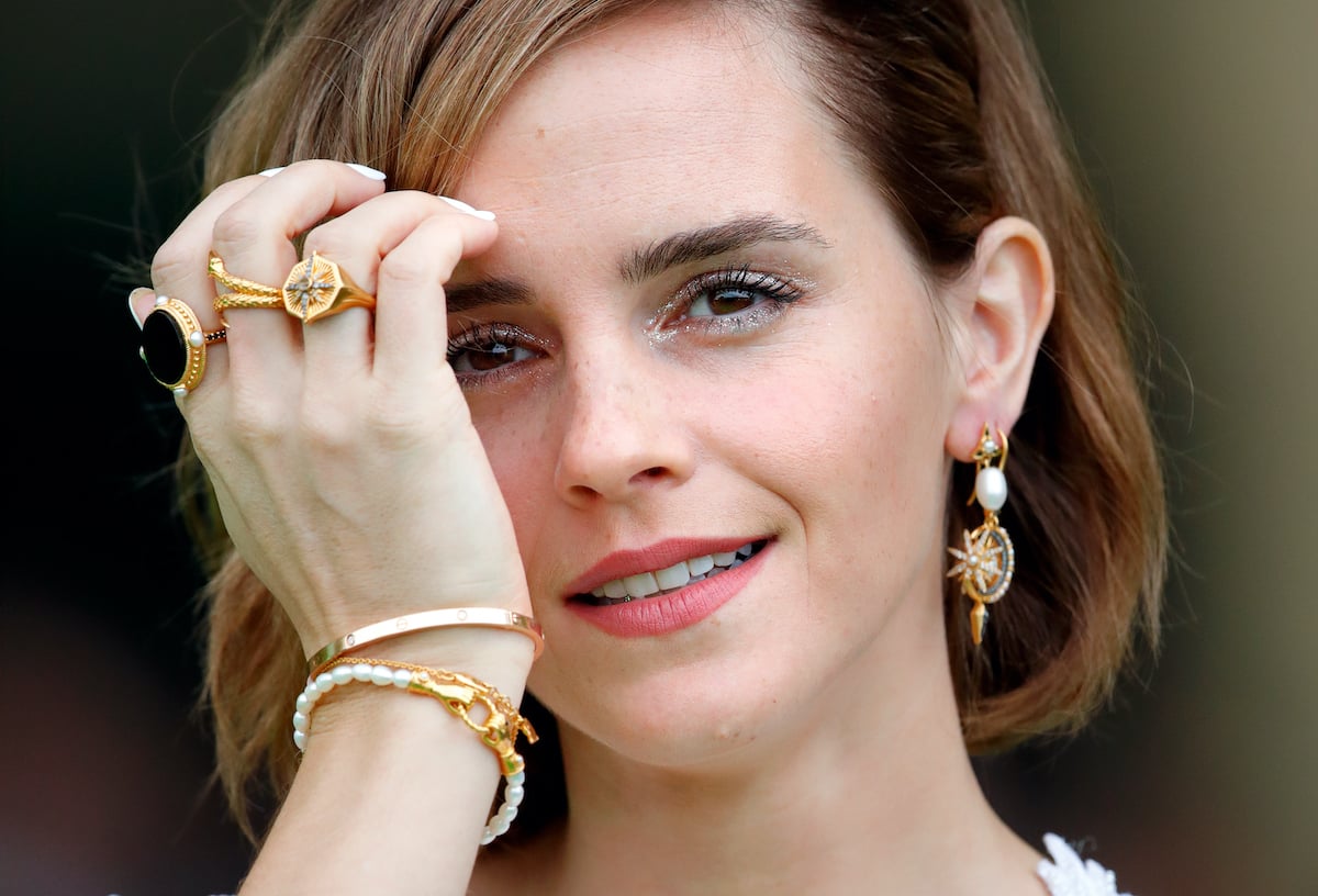 Emma Watson adjusts her hair while taking a photo