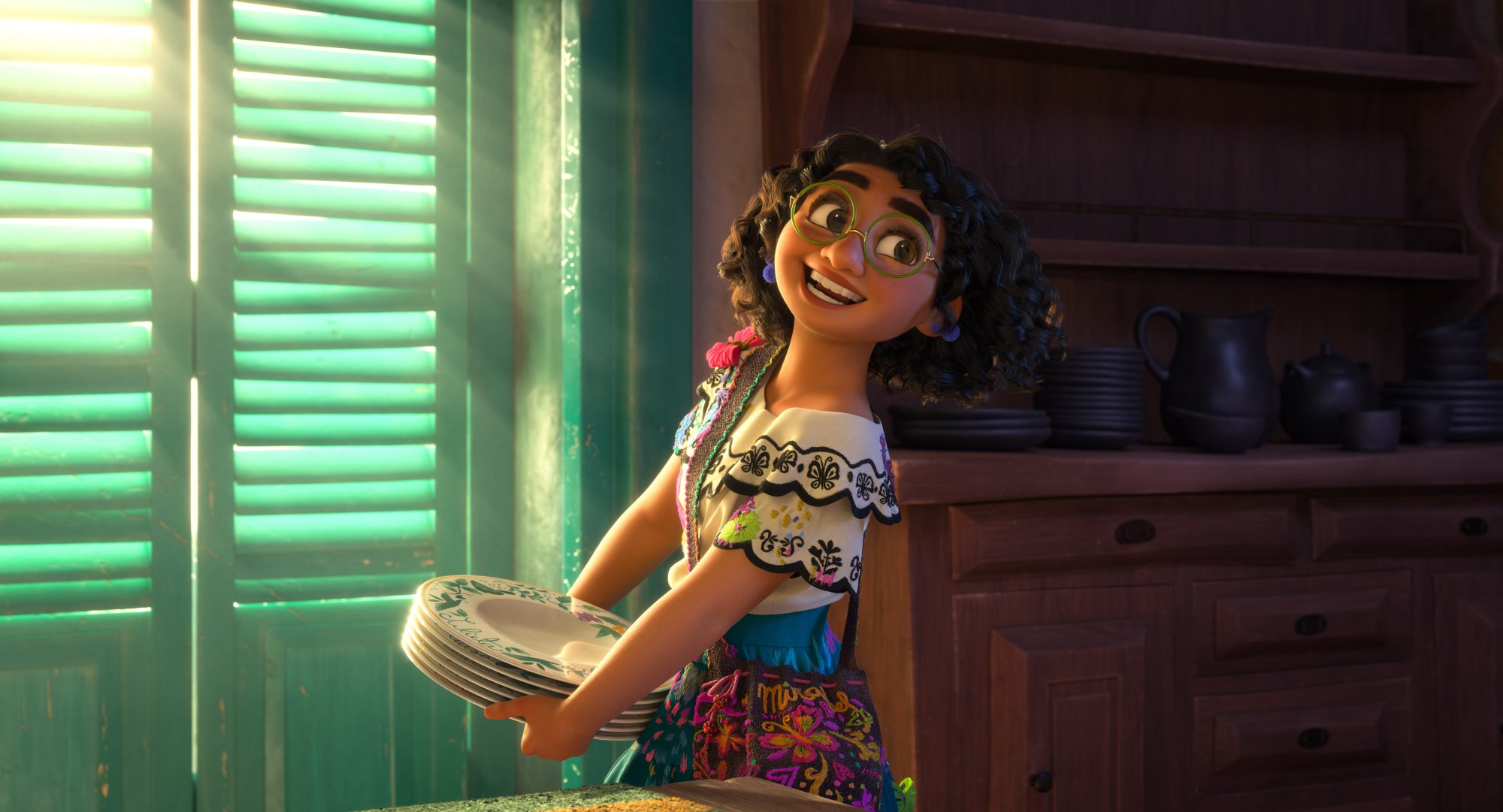 'Encanto' lead Mirabel voiced by Stephanie Beatriz holding a stack of plates while smiling