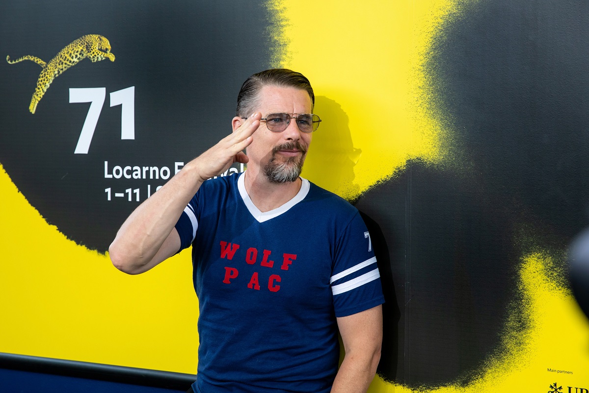 Ethan Hawke giving a salute while wearing sunglasses.