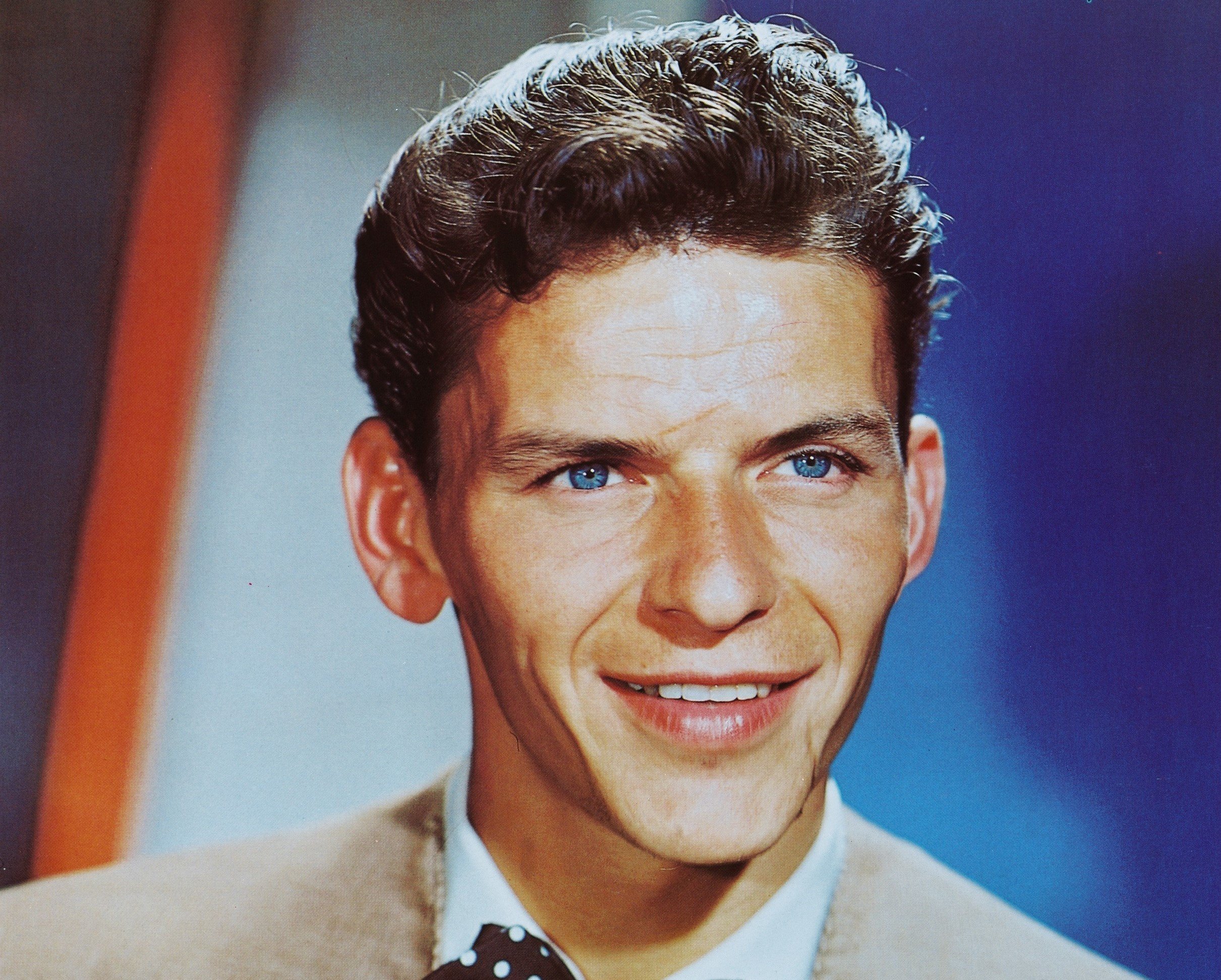 Frank Sinatra wears a tan suit and bowtie.