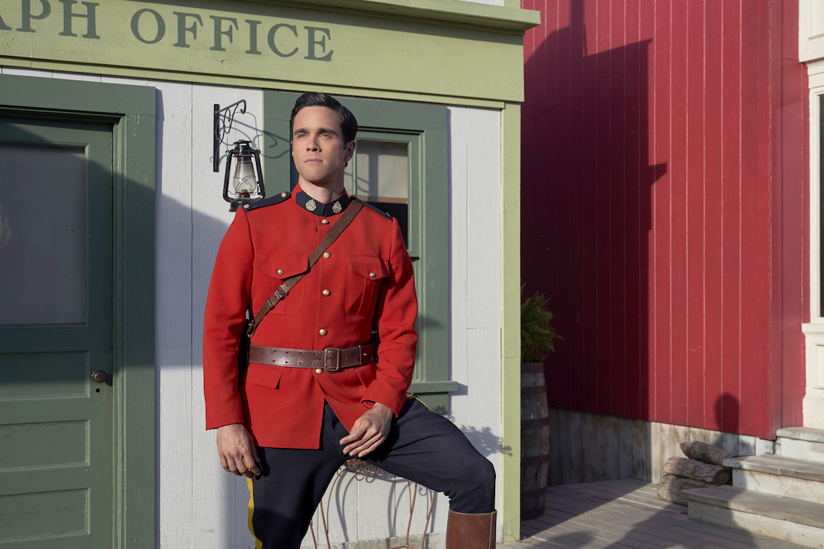 Gabriel, wearing a red Mountie jacketi, standing in front of the telegraph office