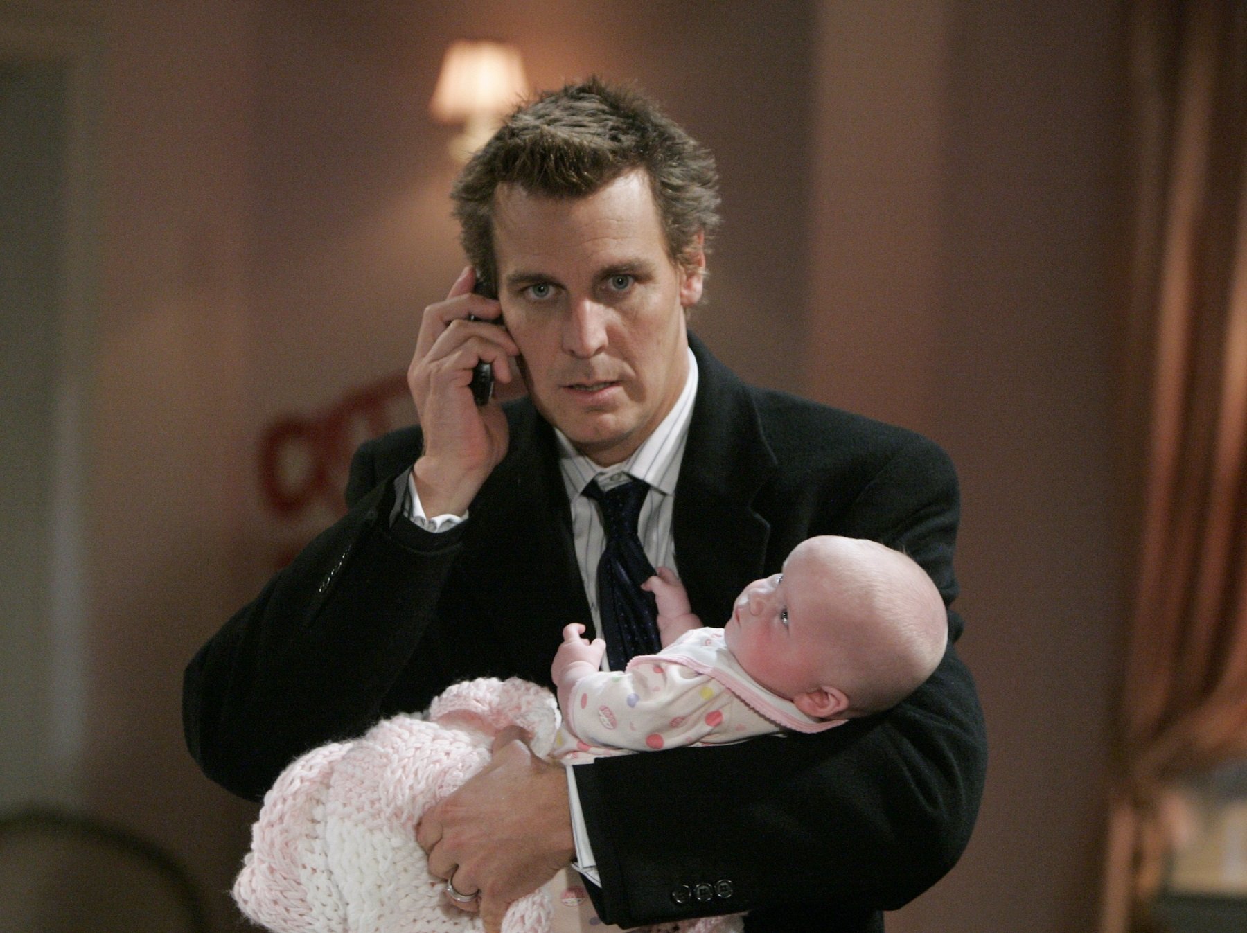 General Hospital star Ingo Rademacher in a tuxedo and holding a baby