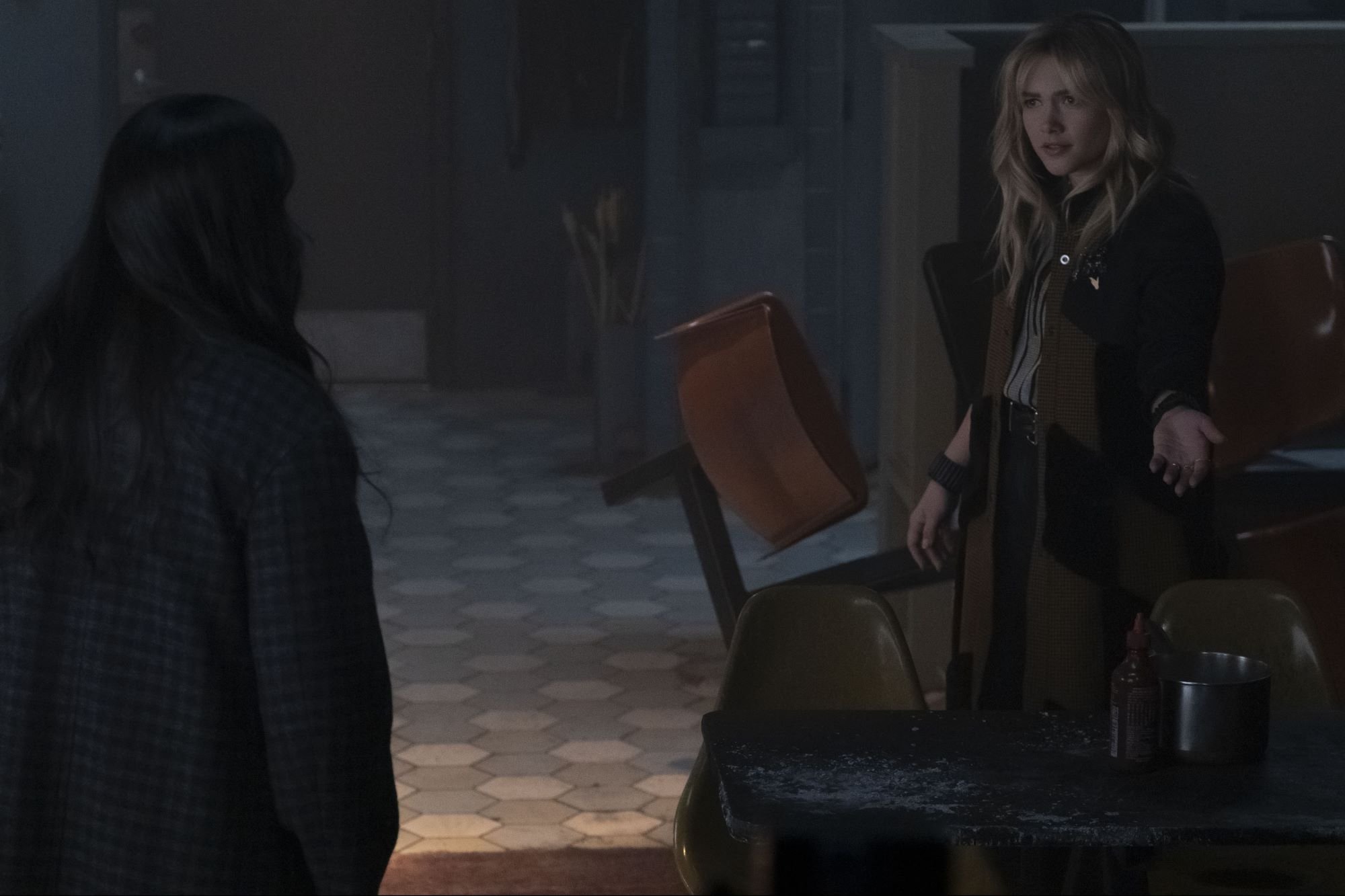 'Hawkeye' stars Hailee Steinfeld and Florence Pugh, who fans want to return for a season 2, act out a scene in Kate's apartment. Kate wears a dark purple plaid coat. Yelena wears a black and brown coat.