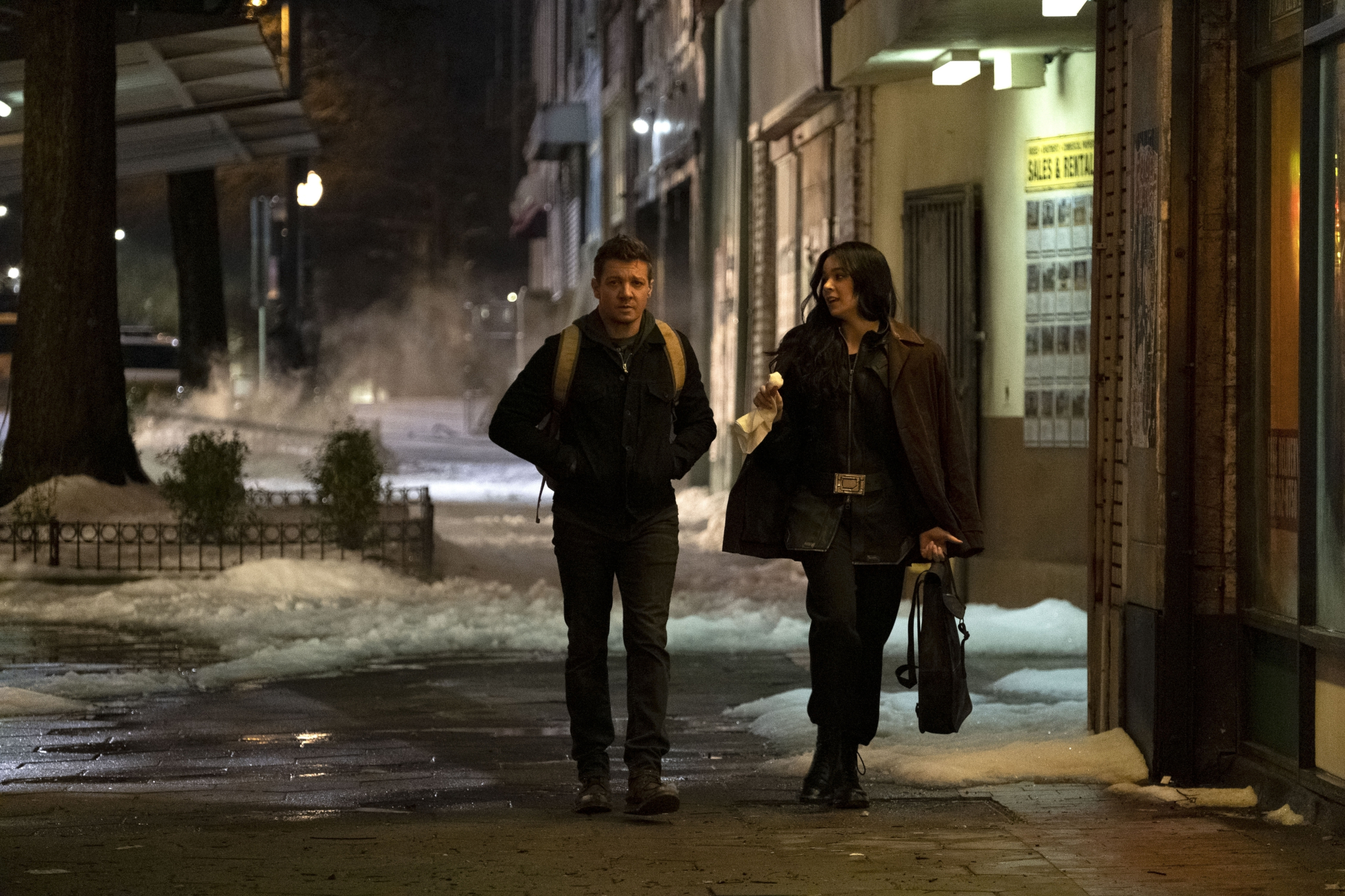 Jeremy Renner and Hailee Steinfeld as Clint Barton and Kate Bishop in in Marvel's 'Hawkeye.' They're walking next to one another down a street in New York City.
