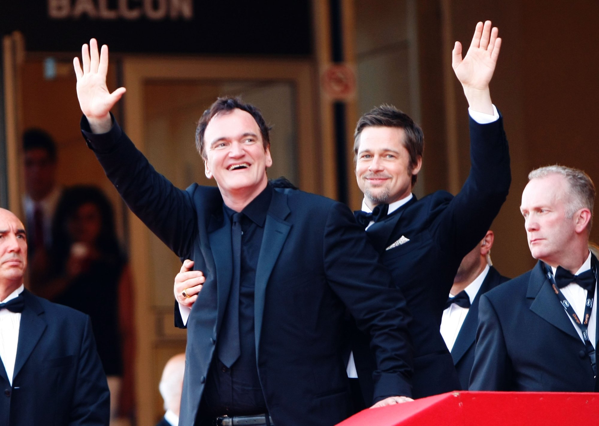 'Inglourious Basterds' Quentin Tarantino and Brad Pitt wearing suits holding a hand up with the other arm around each other