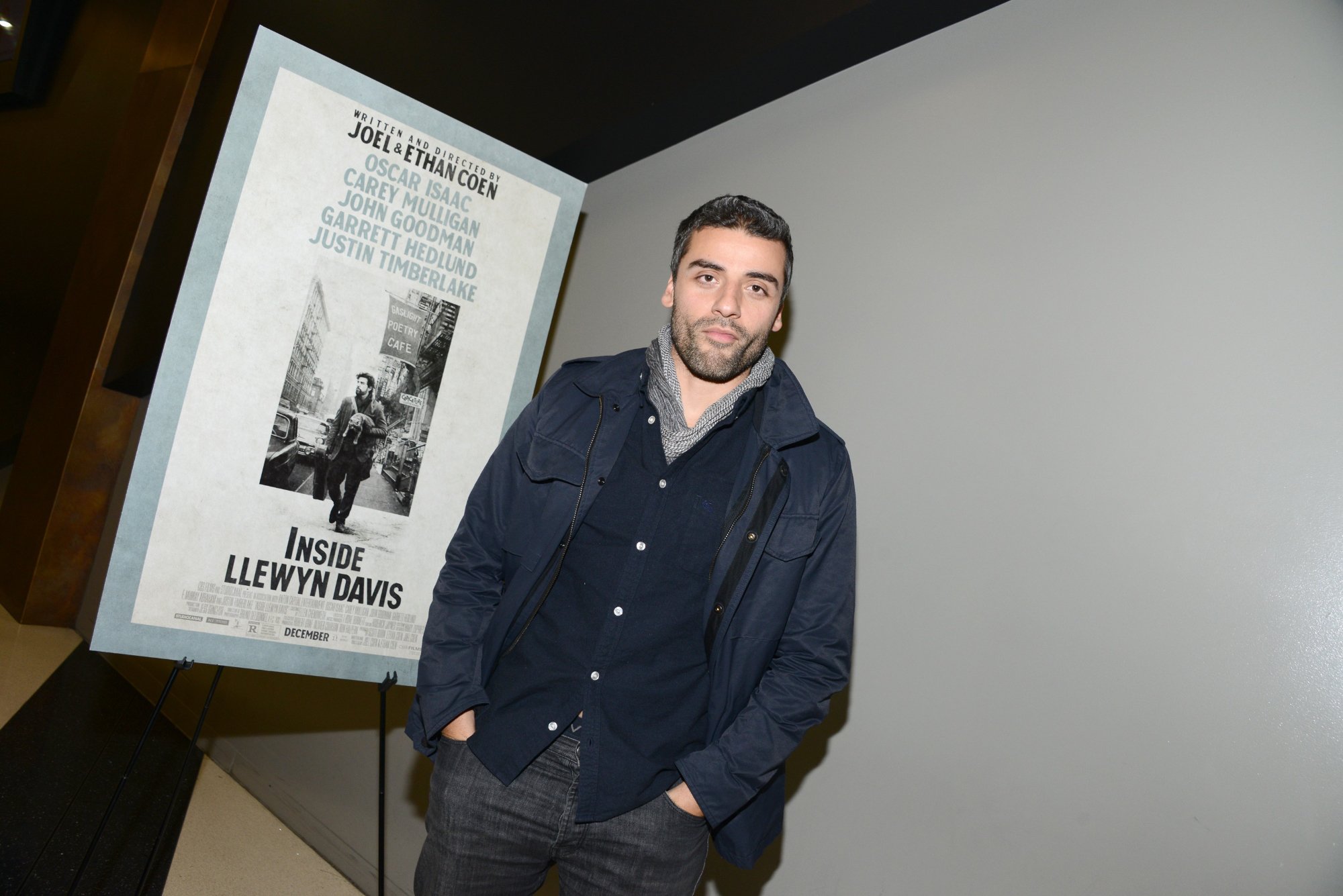 'Inside Llewyn Davis' Oscar Isaac standing in front of movie poster with his hands in his pockets