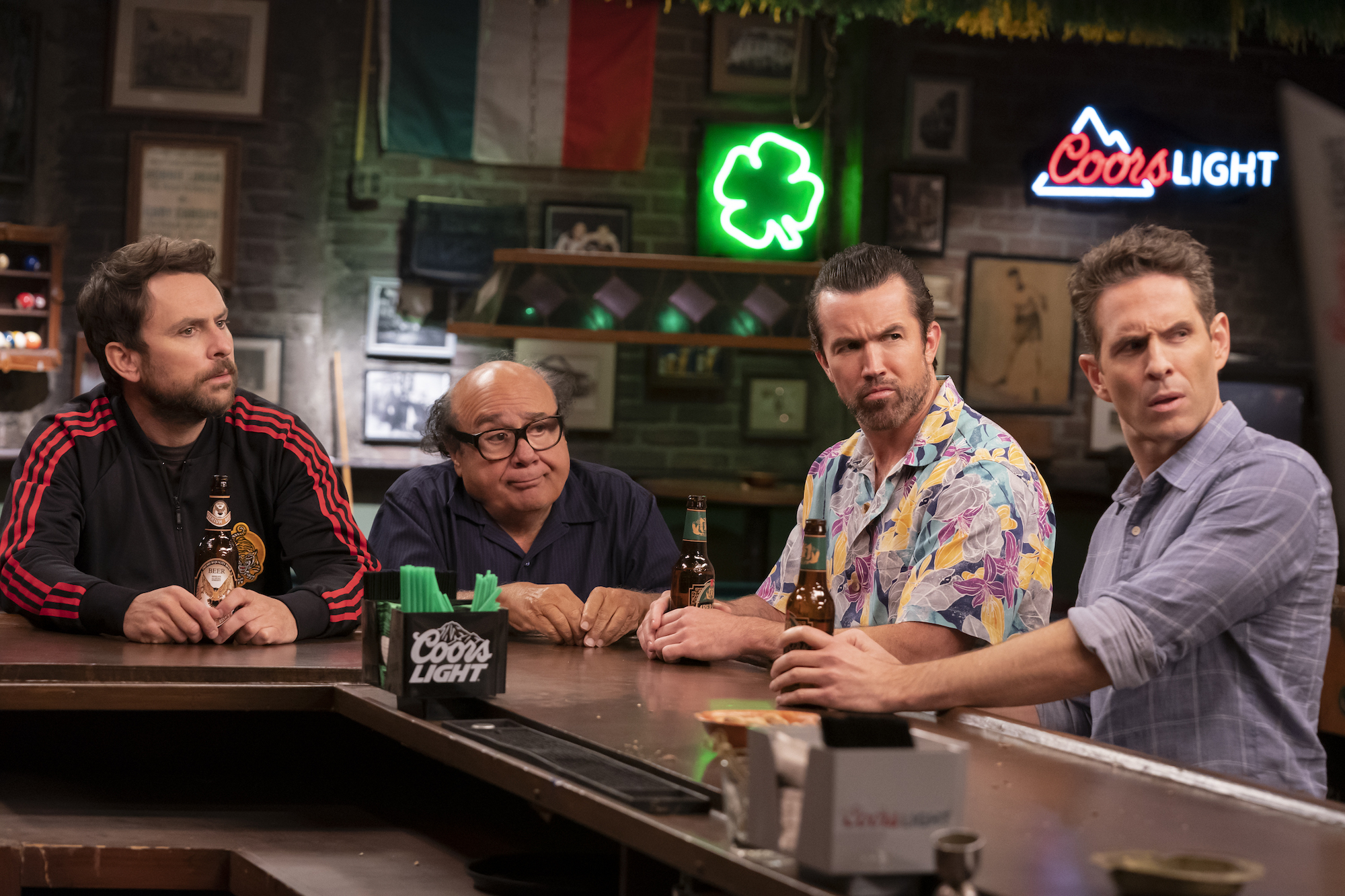 'It's Always Sunny in Philadelphia' Season 15 production still of Charlie Day, Danny DeVito, Rob McElhenney, and Glen Howerton sitting at a bar while looking confused.