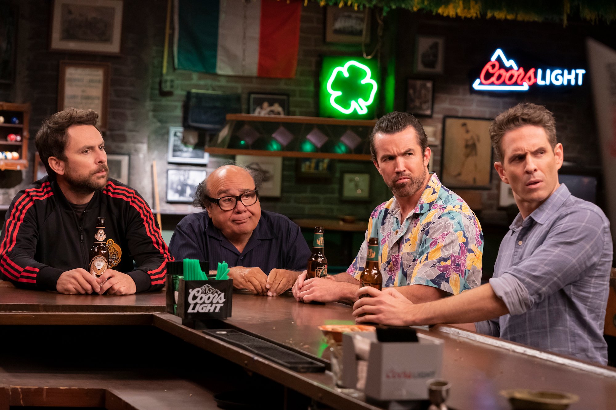 'It's Always Sunny in Philadelphia' Season 15 production still of Charlie Day, Danny DeVito, Rob McElhenney, and Glen Howerton sitting at a bar while looking confused.