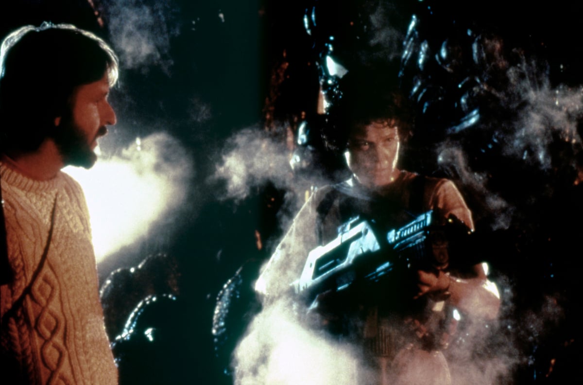 Sigourney Weaver as Ripley in ‘Aliens’ holds a weapon as director James Cameron looks on