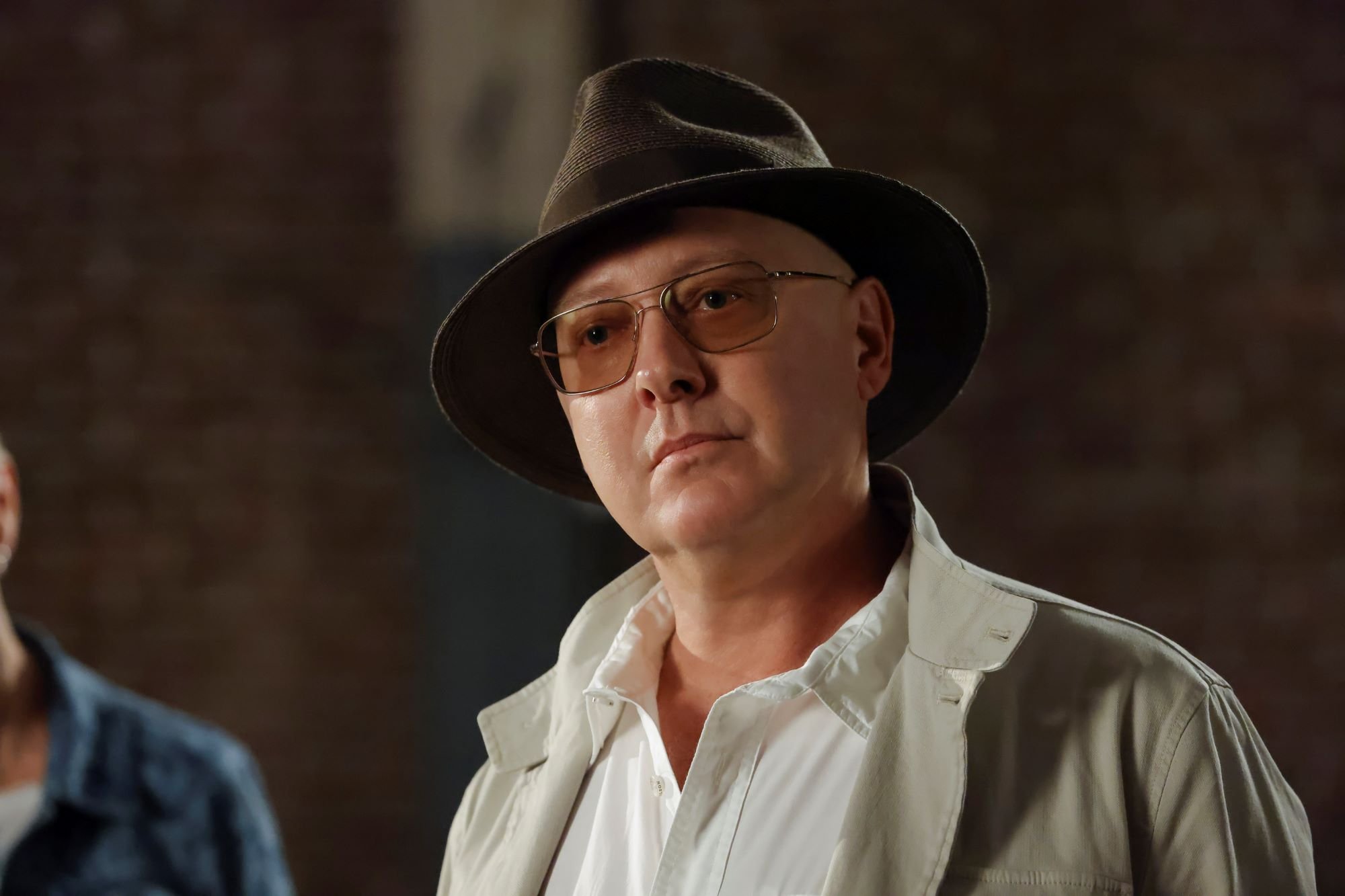 'The Blacklist' star James Spader, in character as Red, wears a brown fedora hat, tinted glasses, and a white jacket over a white button-up shirt.