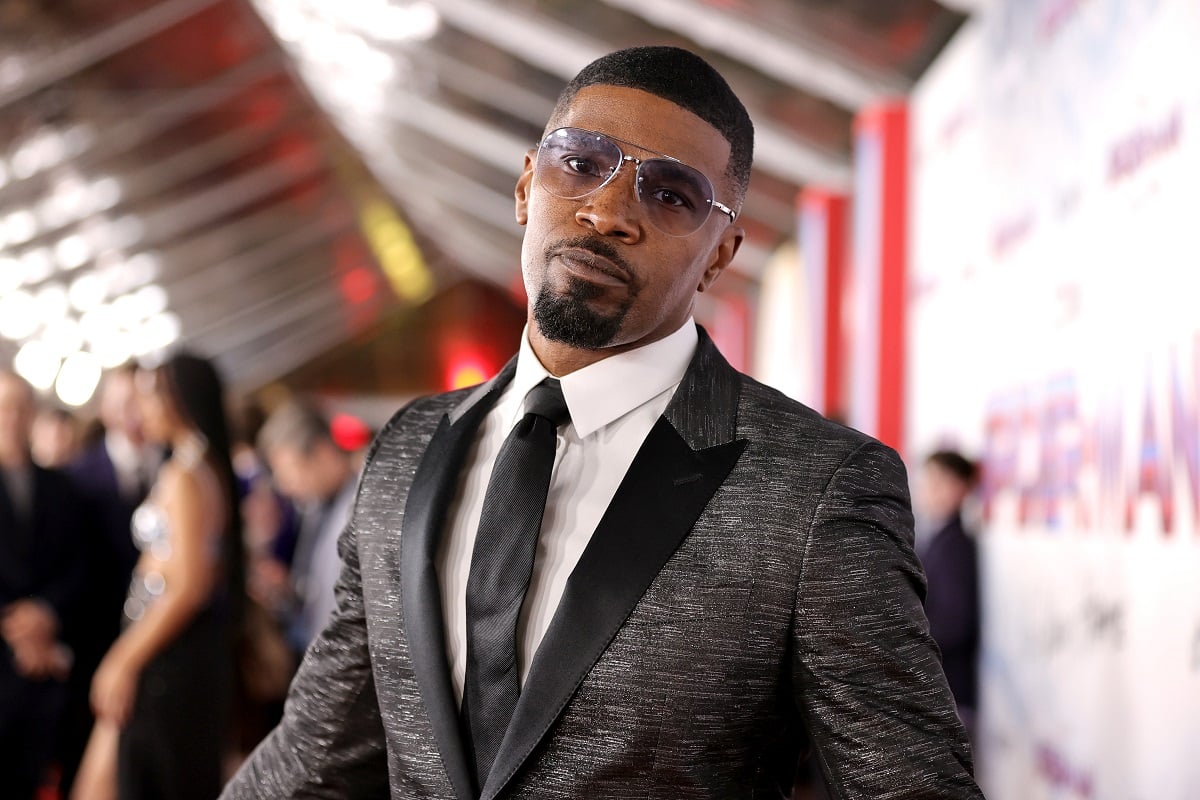 Jamie Foxx wearing a silver business outfit and sunglasses.