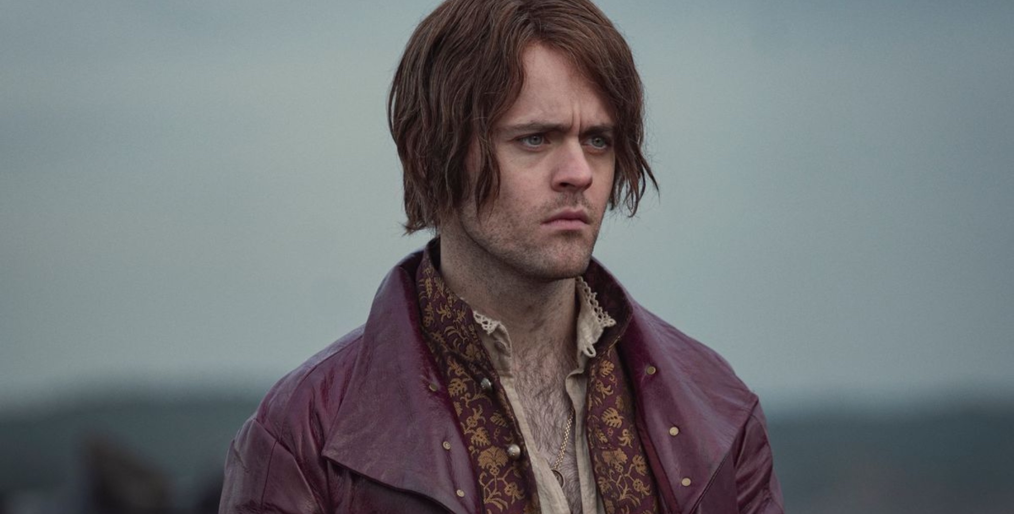 Jaskier in 'The Witcher' Season 2 wearing red leather coat.