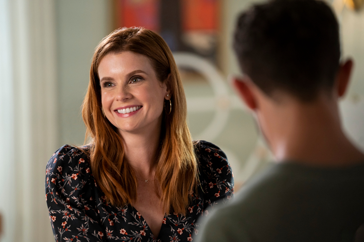 Smiling JoAnna Garcia Swisher with the back of a man's head in the foreground in 'Sweet Magnolias' Season 2