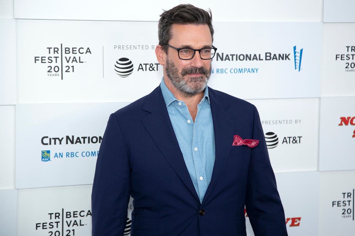 Jon Hamm smiling in front of a white background