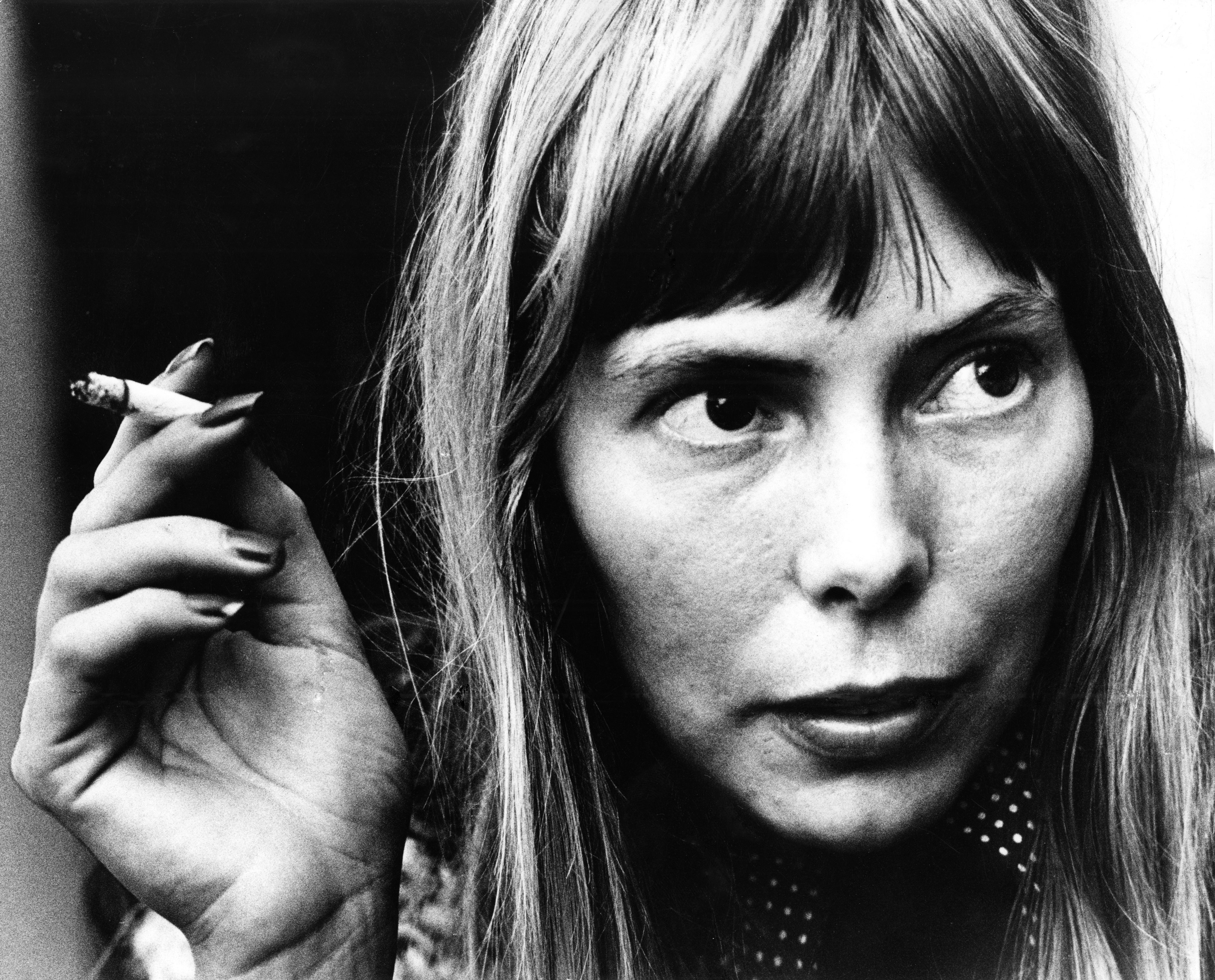 A black and white picture of Joni Mitchell holding a cigarette.