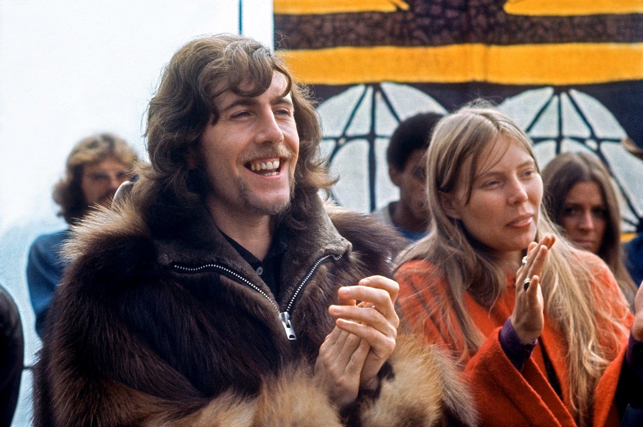 Graham Nash wears a brown fur coat and Joni Mitchell wears an orange coat.