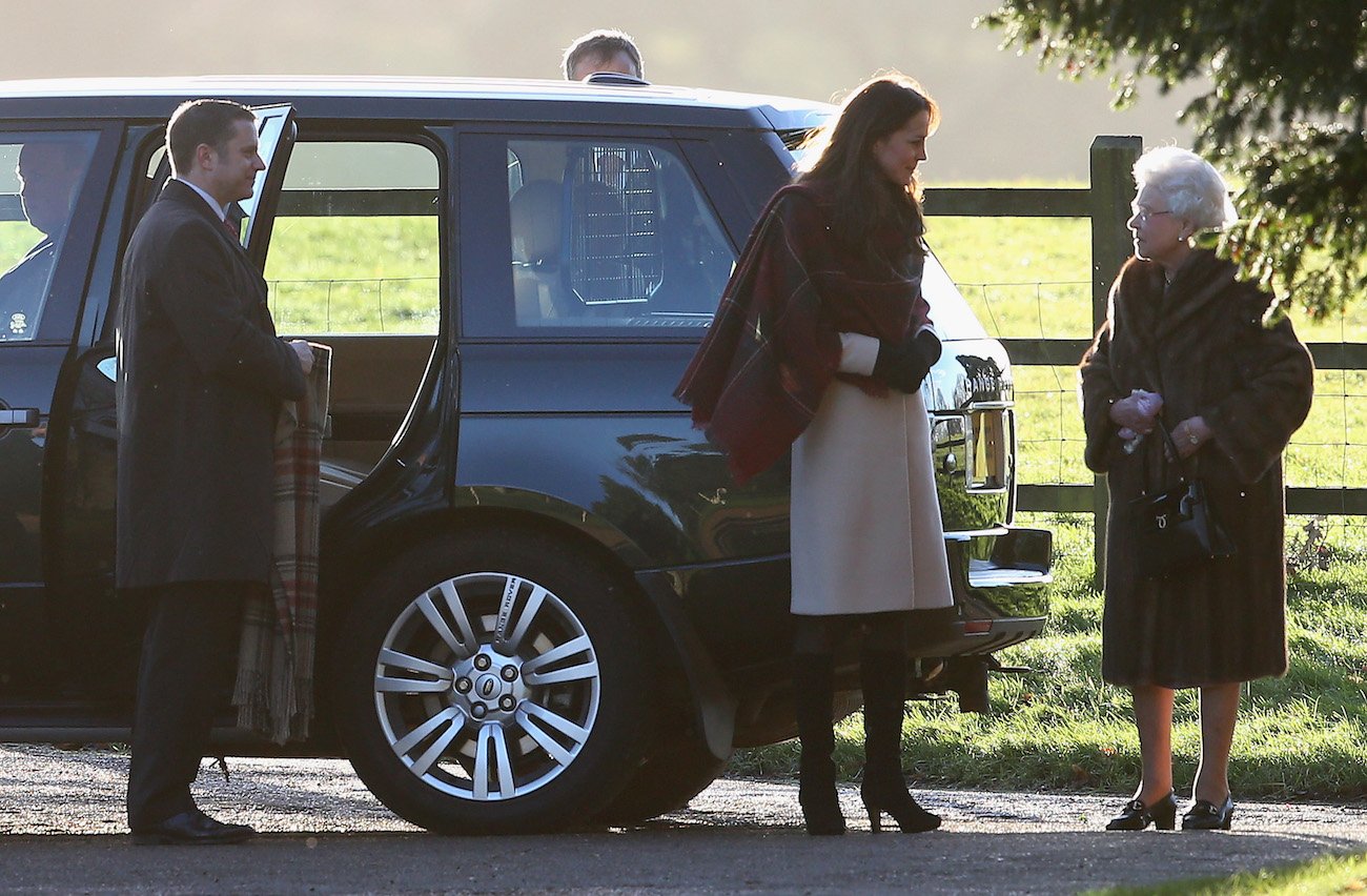 Kate Middleton stands next to Queen Elizabeth after exiting a car on Christmas Day 2013
