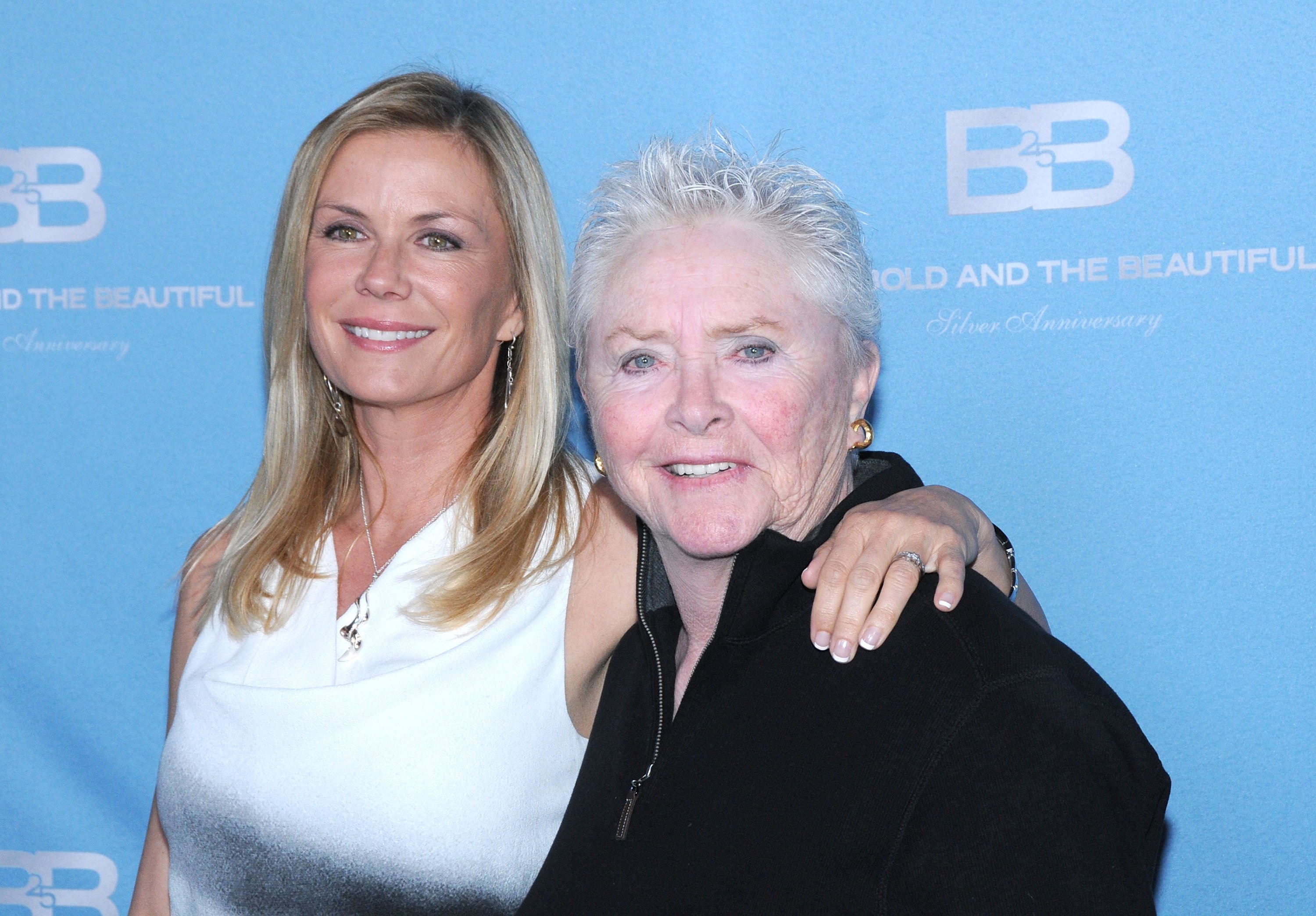 'The Bold and the Beautiful' actor Katherine Kelly Lang in a white blouse and Susan Flannery in a black jacket, share a side hug.
