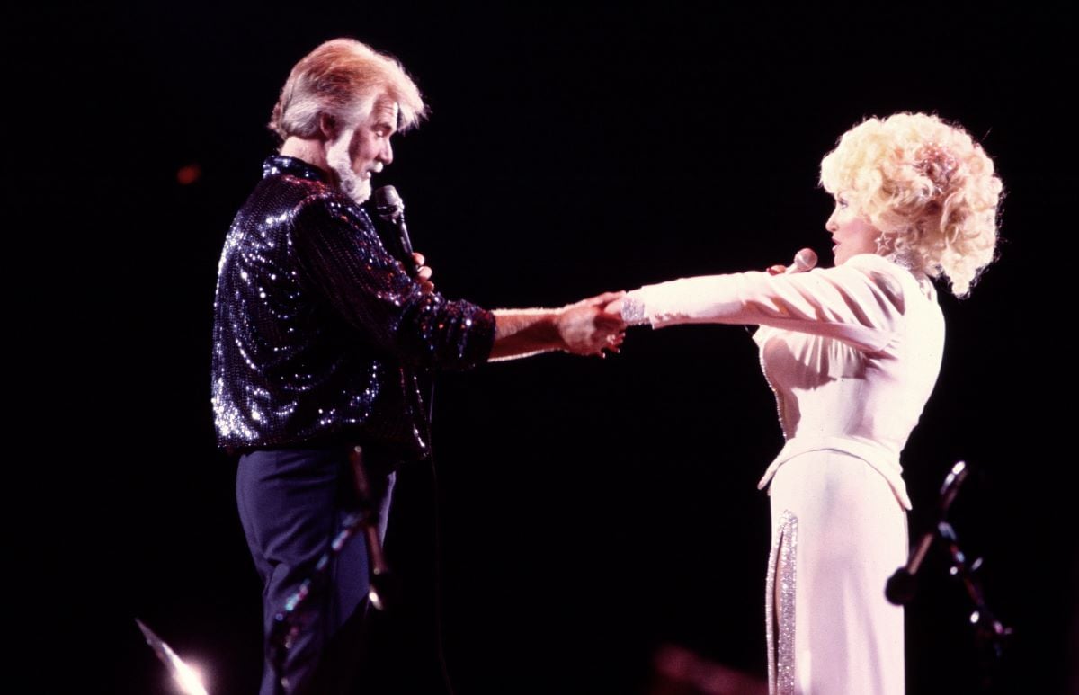 Kenny Rogers in a sequin shirt and Dolly Parton in a pink dress, performing together onstage
