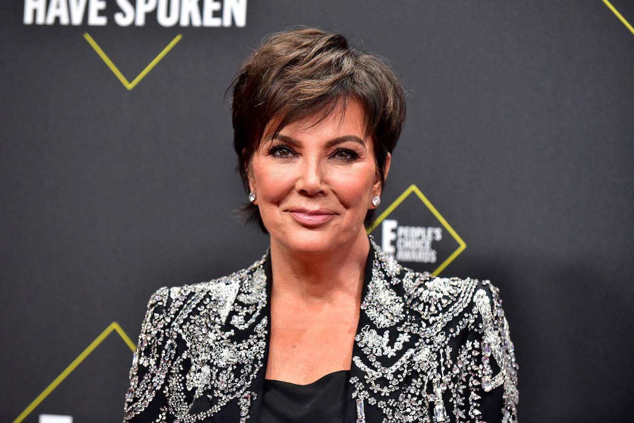 Kris Jenner smiling in front of a gray background