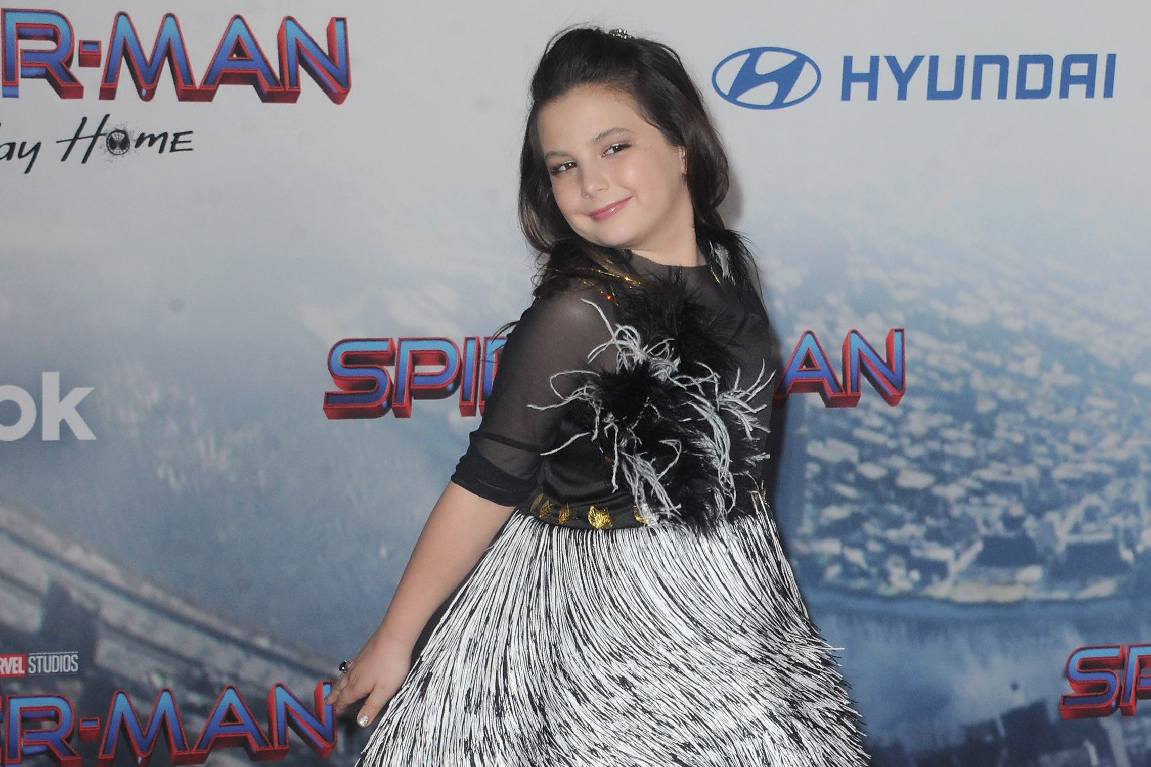 Lexi Rabe, who plays Morgan Stark, Tony Stark's daughter, in the MCU, attends the 'Spider-Man: No Way Home' premiere. Rabe wears a black and white dress with feathers.