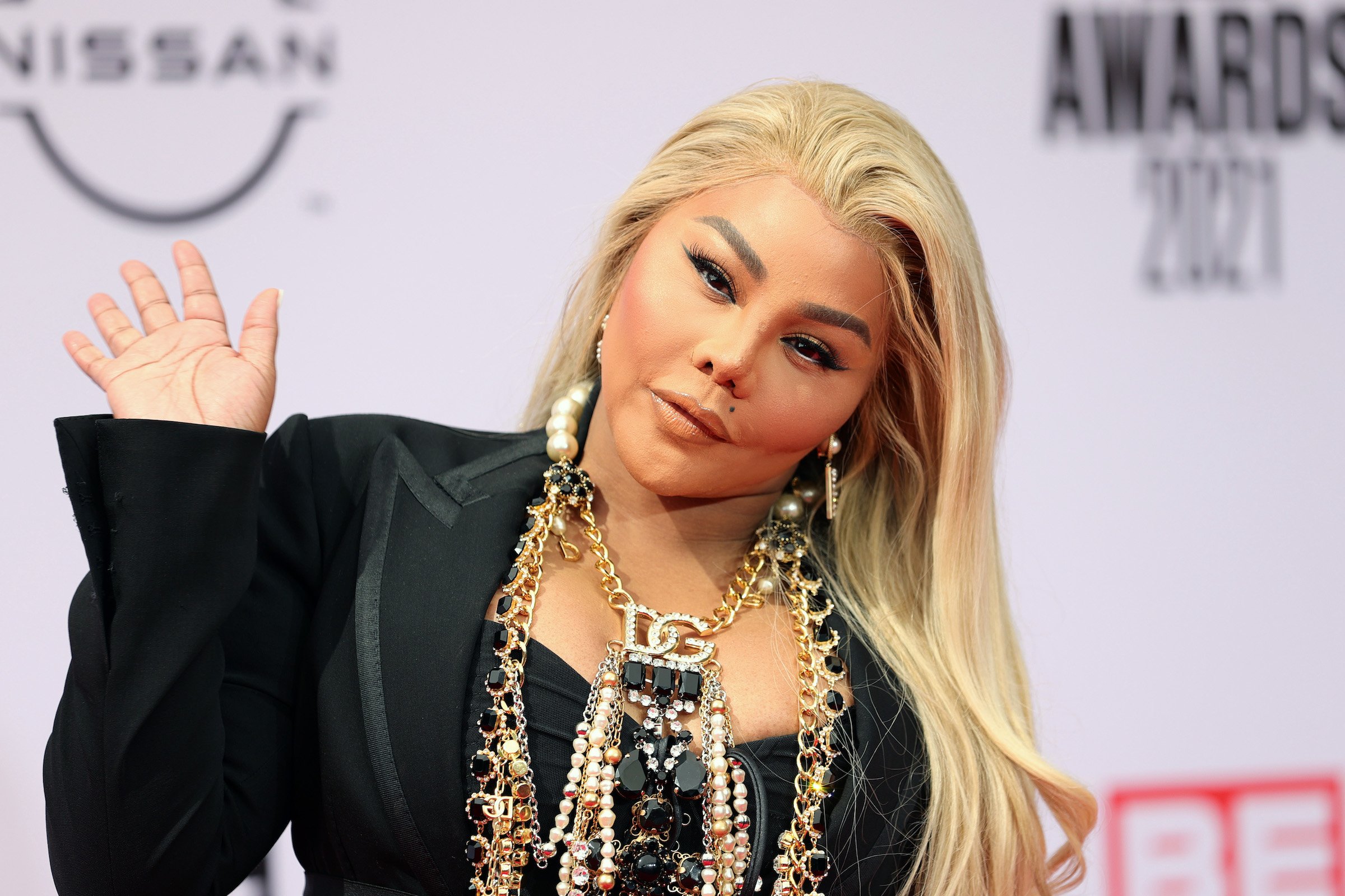 Lil' Kim wearing black and waving at the camera