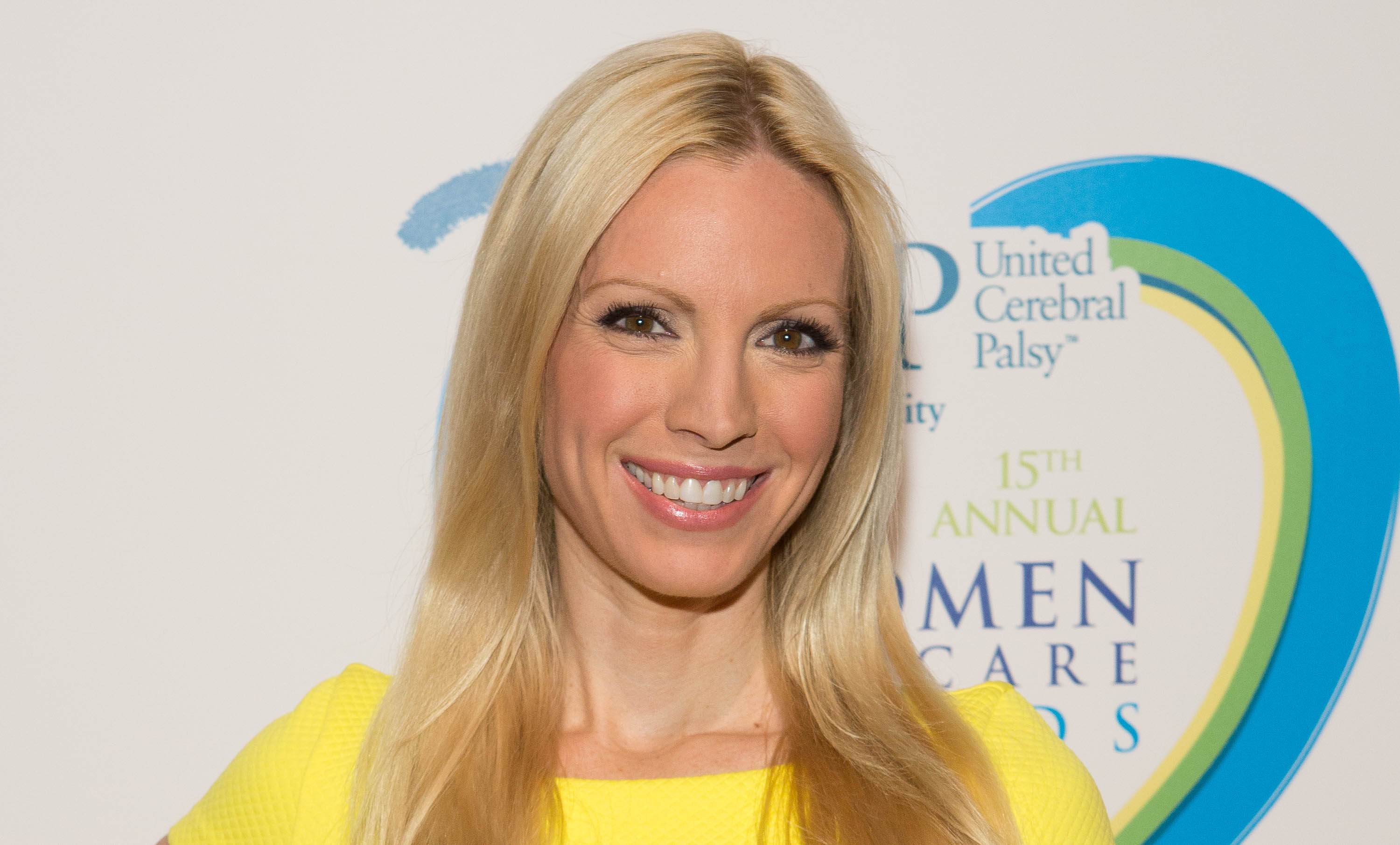 'Passions' actor Liza Huber wearing a yellow dress, and smiling.