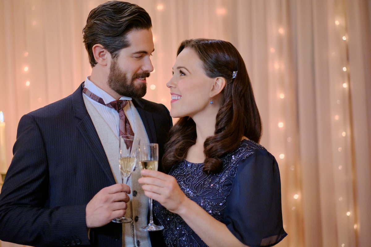 Lucas and Elizabeth holding champagne flutes and looking lovingly at each other in 'When Calls the Heart' Season 8