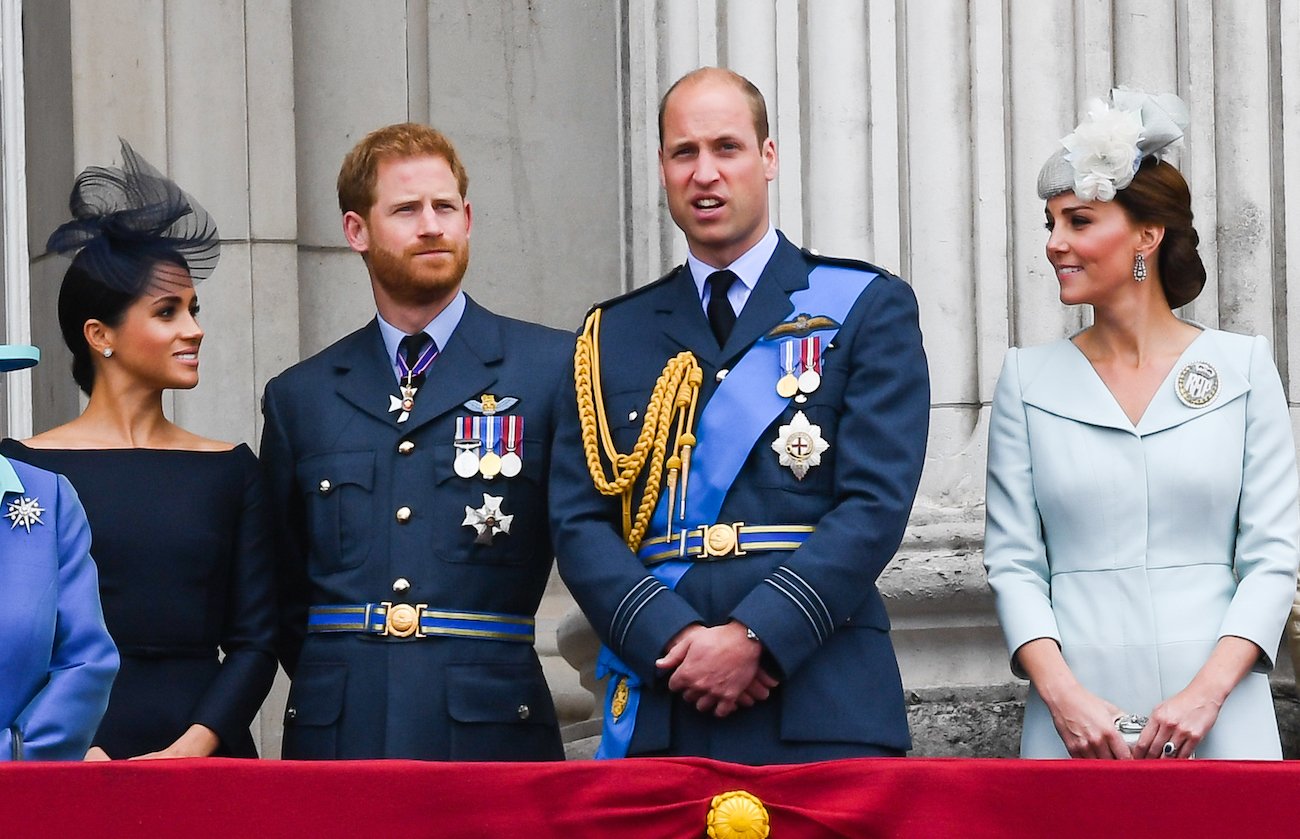 (L-R) Meghan Markle, Prince Harry, Prince William, and Kate Middleton standing on a balcony