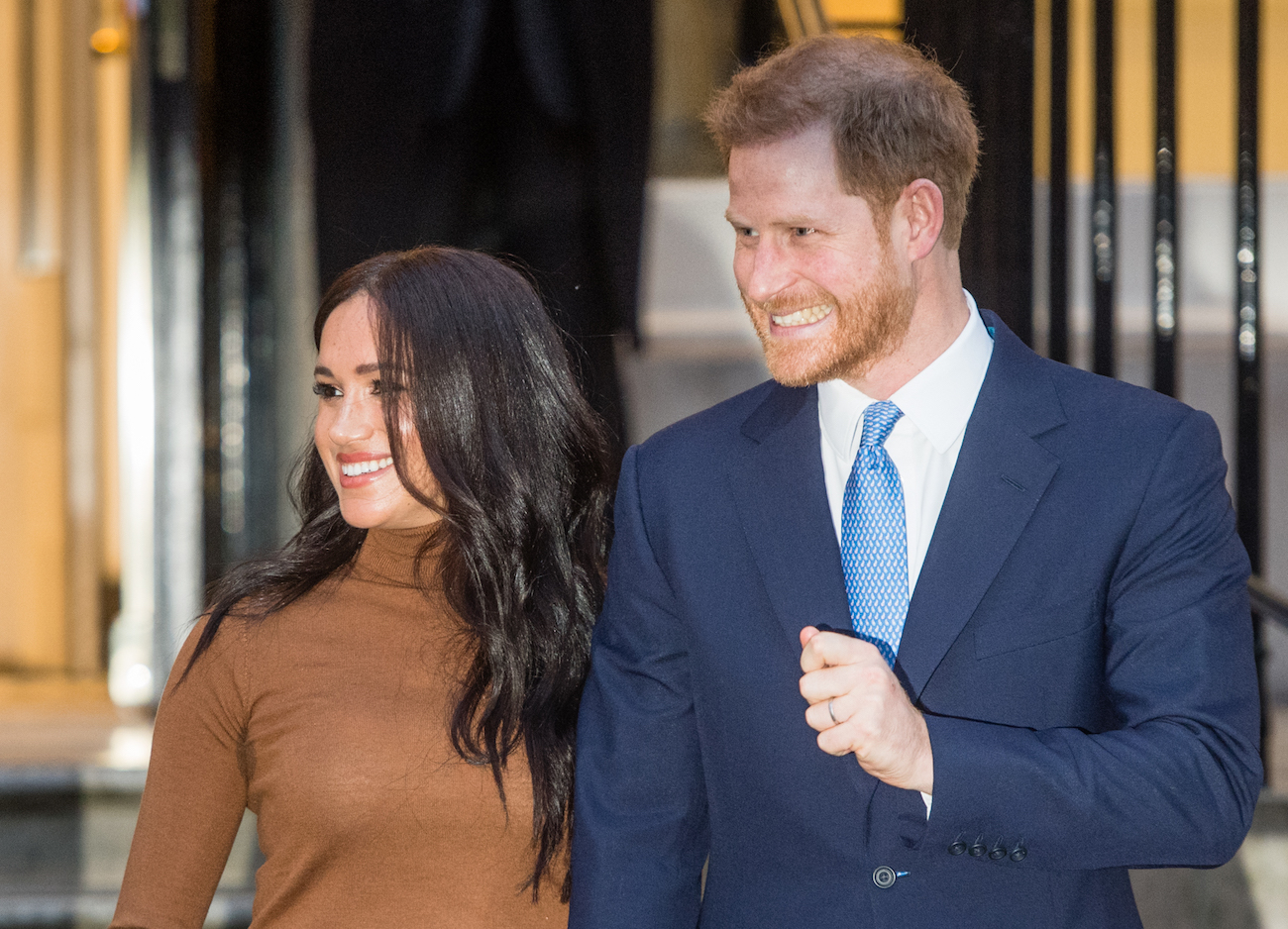 Meghan Markle and Prince Harry smiling, looking to the side