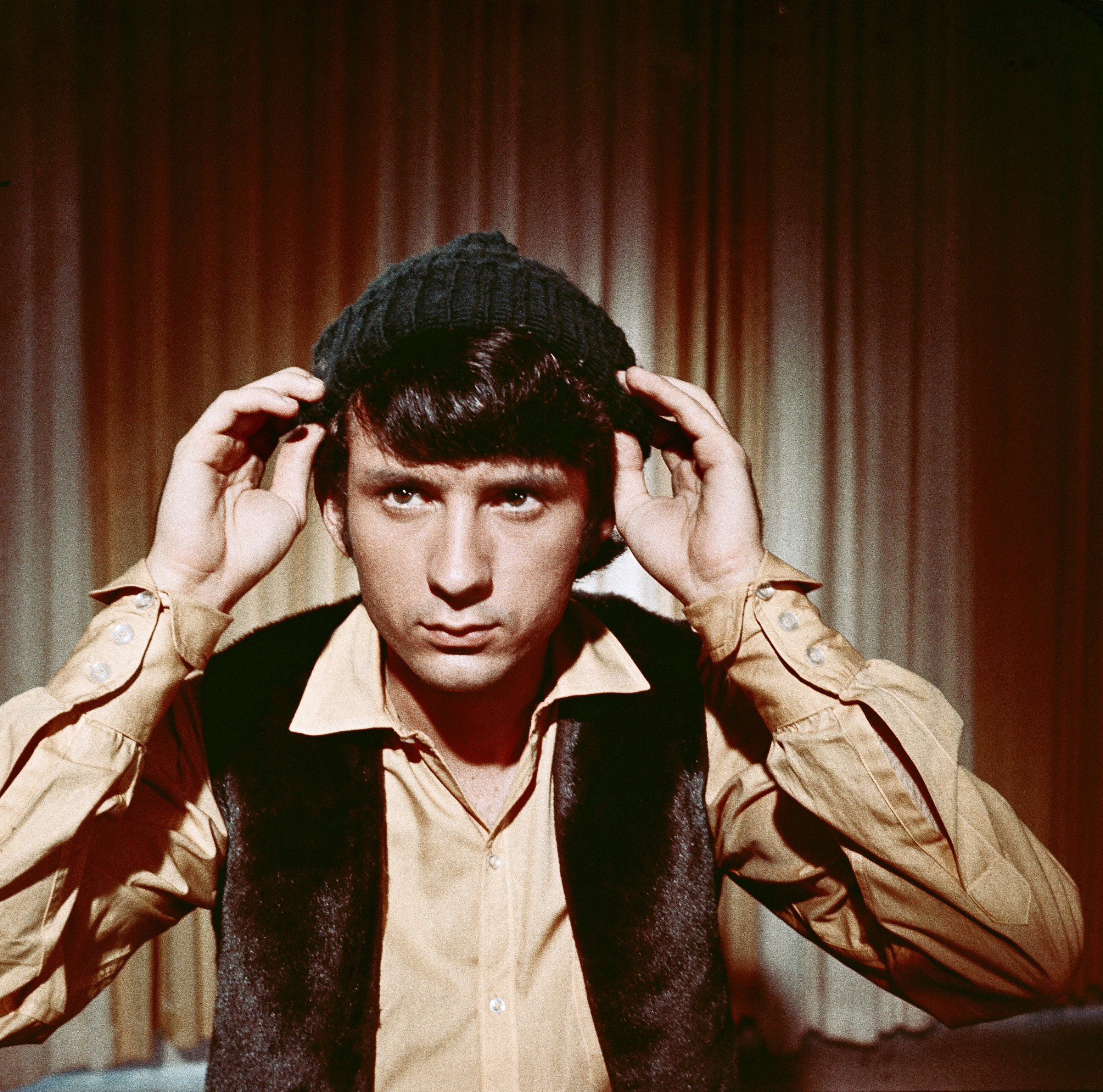 Michael Nesmith of The Monkees is pictured here in a green hat and black vest and long-sleeved brown shirt