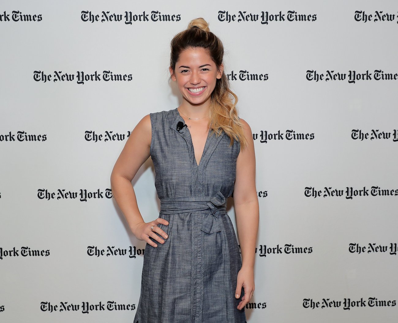 Molly Yeh smiles wearing a blue dress with one hand on her hip
