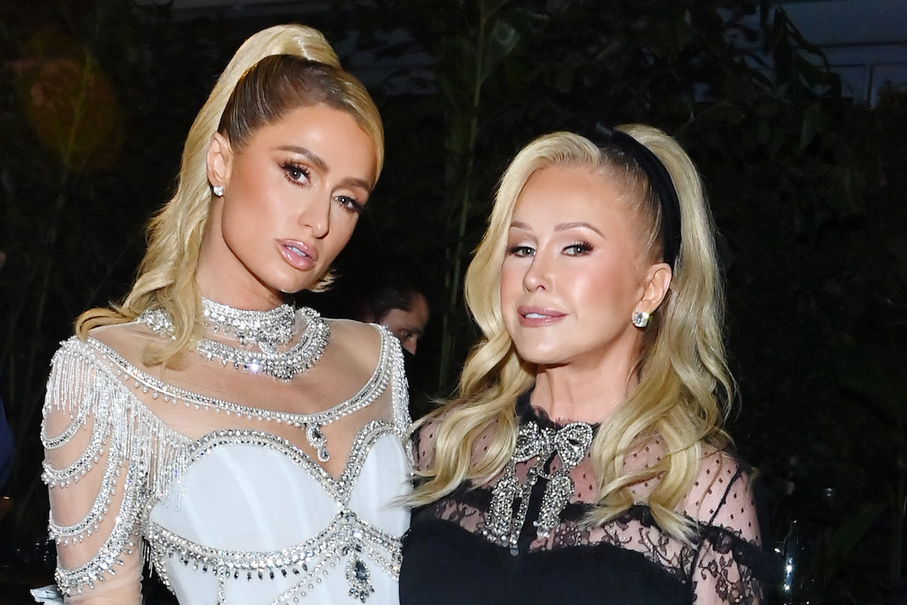 Paris Hilton wears a white dress as she stands next to Kathy Hilton who wears a black dress